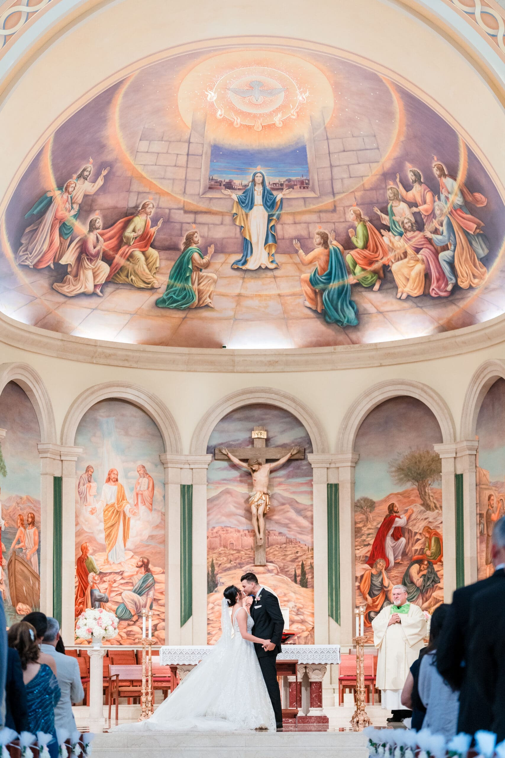 Tall shot capturing the 'I do' kiss at the altar of St. James Cathedral, with the stunning artwork in the dome above the altar.