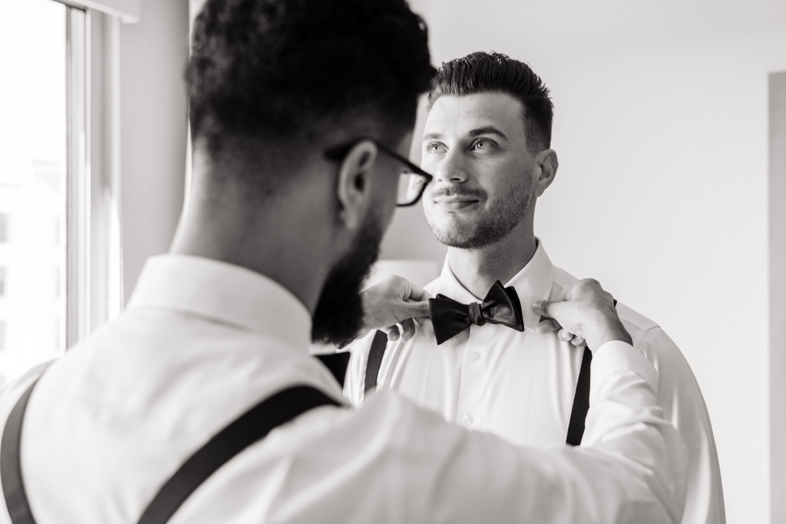 Black and white shot of Javier's best man fixing his bow tie.