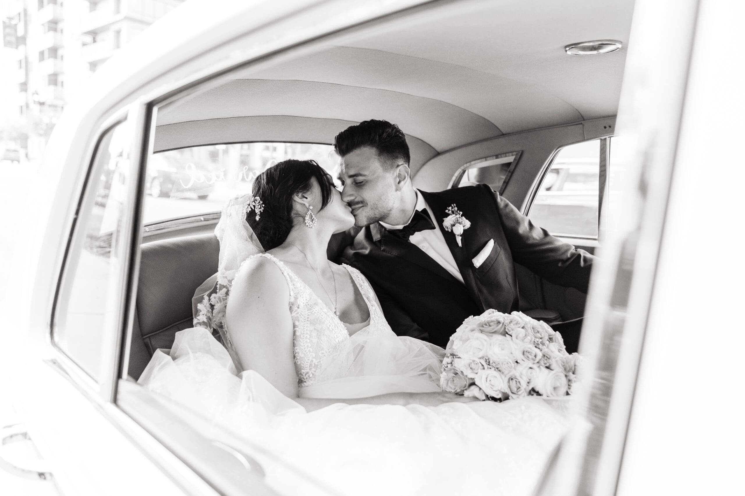 Black and White -Close-up shot of Jessica and Javier kissing in the back of the car after leaving St. James Cathedral - captured by Published & Award-Winning Orlando Wedding Photographer And Videographer - Jerzy Nieves