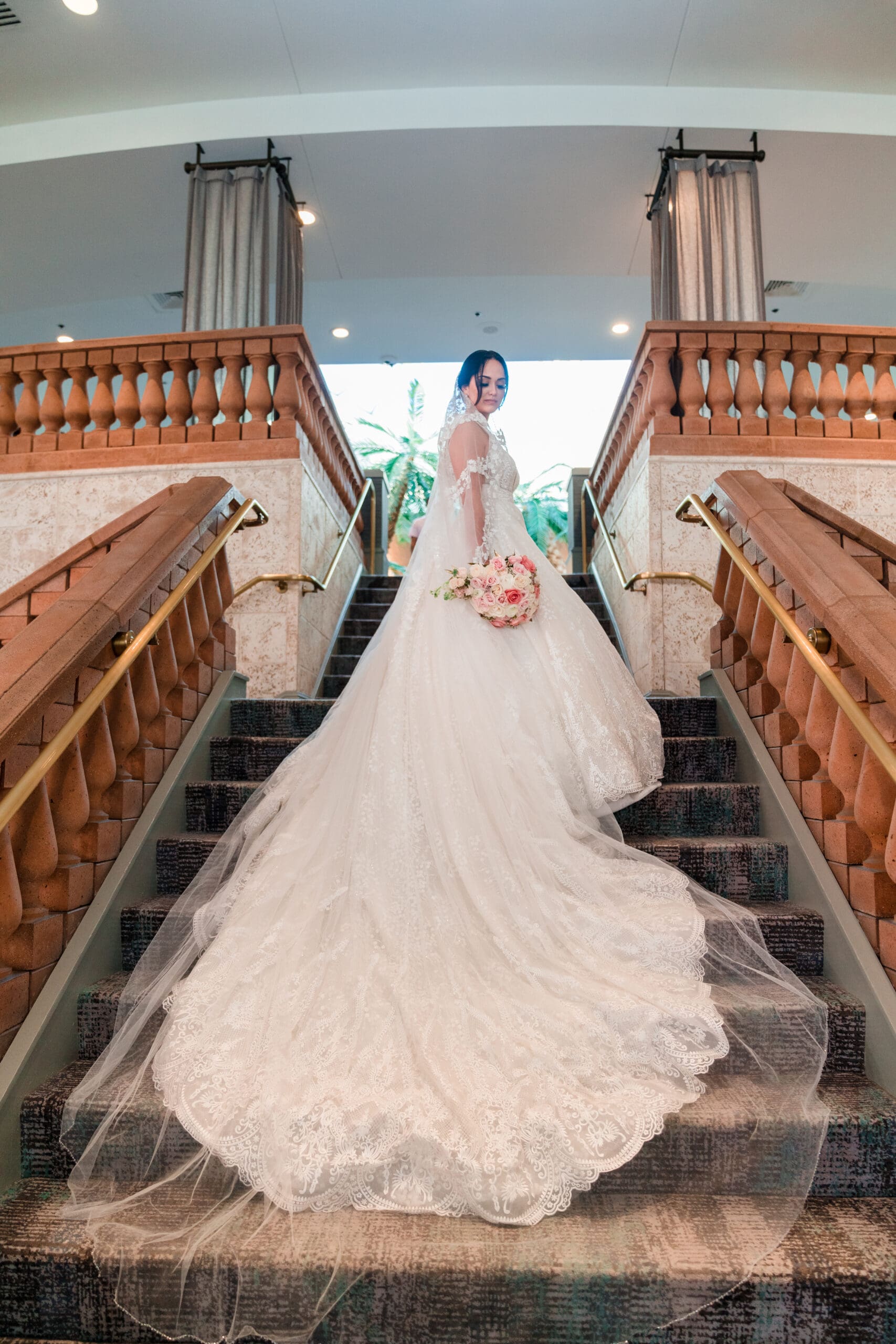 Jessica standing at the top of the stairs at Caribe Royale Orlando, her dress flowing gracefully down the stairs.