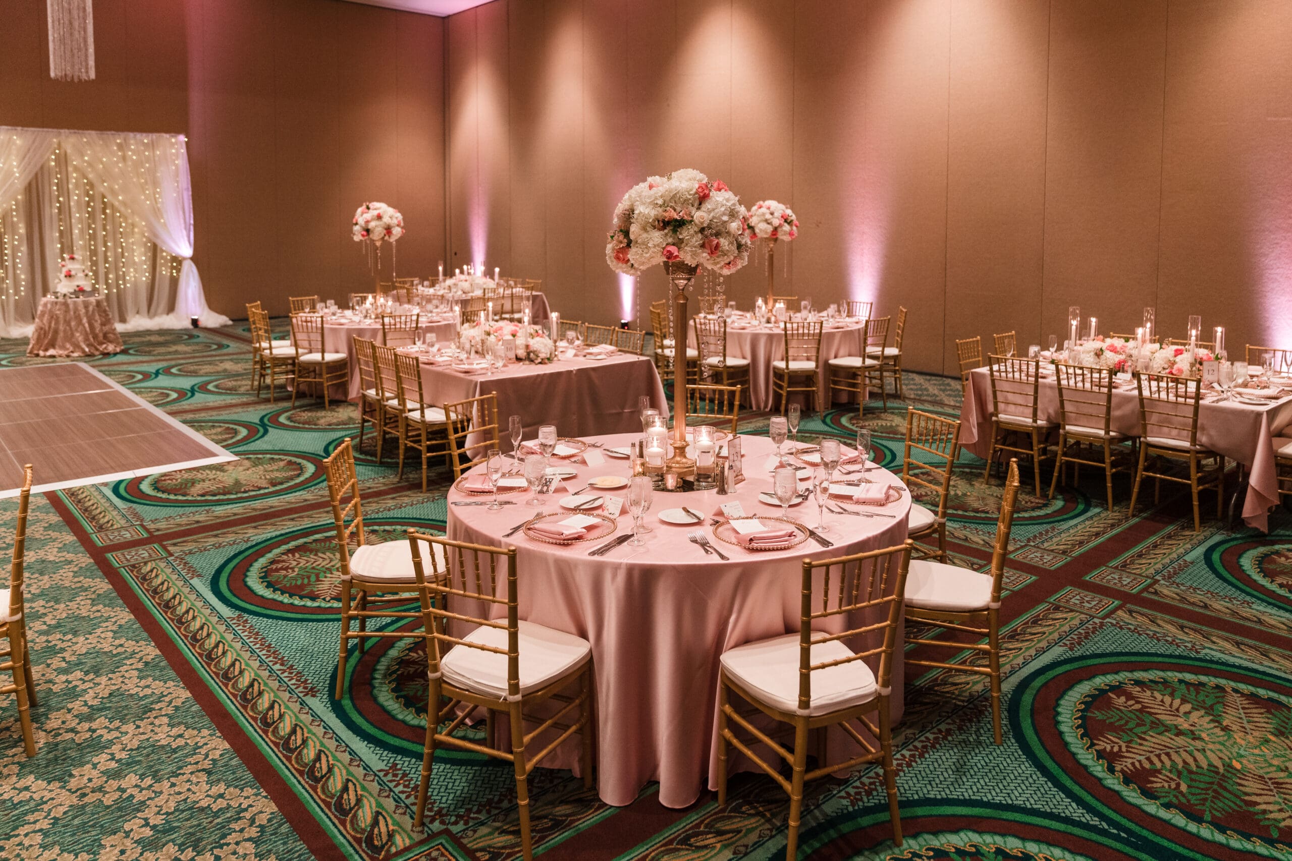 Empty reception area before the wedding ceremony at Orlando Royale Caribe Reception, featuring pink tablecloths, white rose flower centerpieces with pink roses, and elegant decor