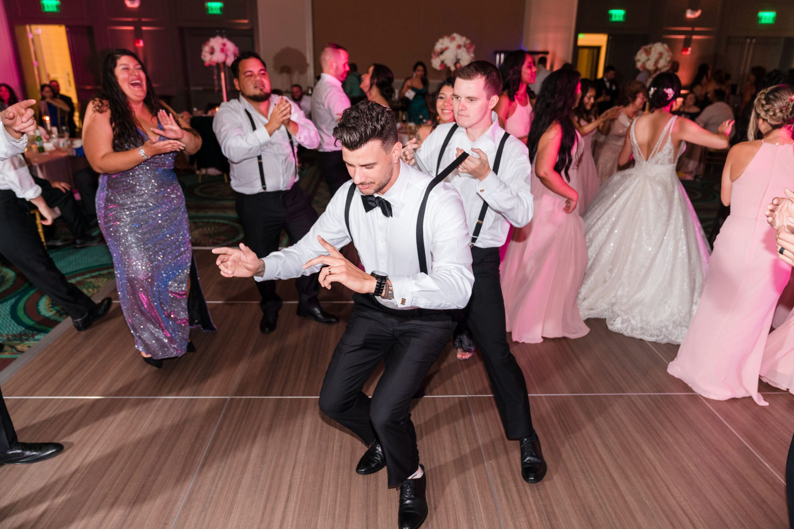 Wide shot capturing Javier dancing on the floor surrounded by guests, everyone laughing and having fun at the Orlando Royale Caribe reception center, beautifully photographed by Jerzy Nieves Photography.