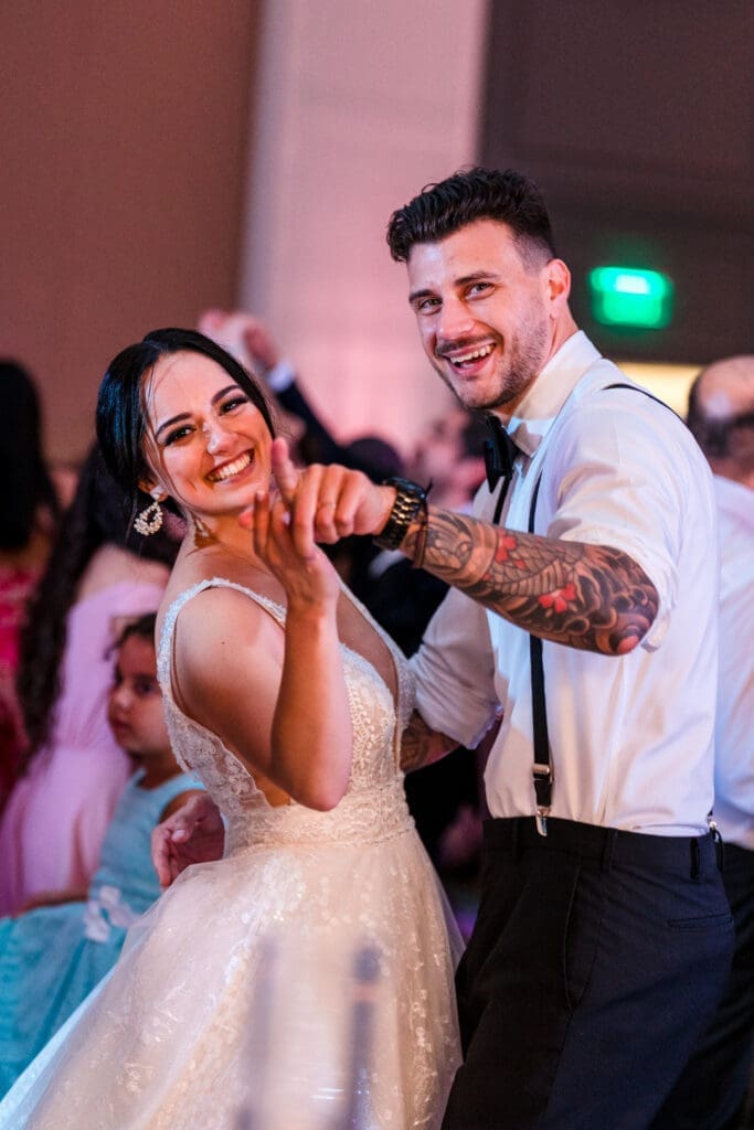 Jessica and Javier dancing together with huge smiles on their faces, looking at the camera at the Orlando Royale Caribe reception center, captured by Jerzy Nieves Photography.