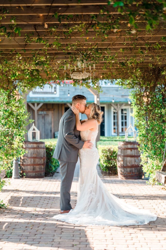 Tall shot of Delisa kissing Preston under Hidden Barn's walkway