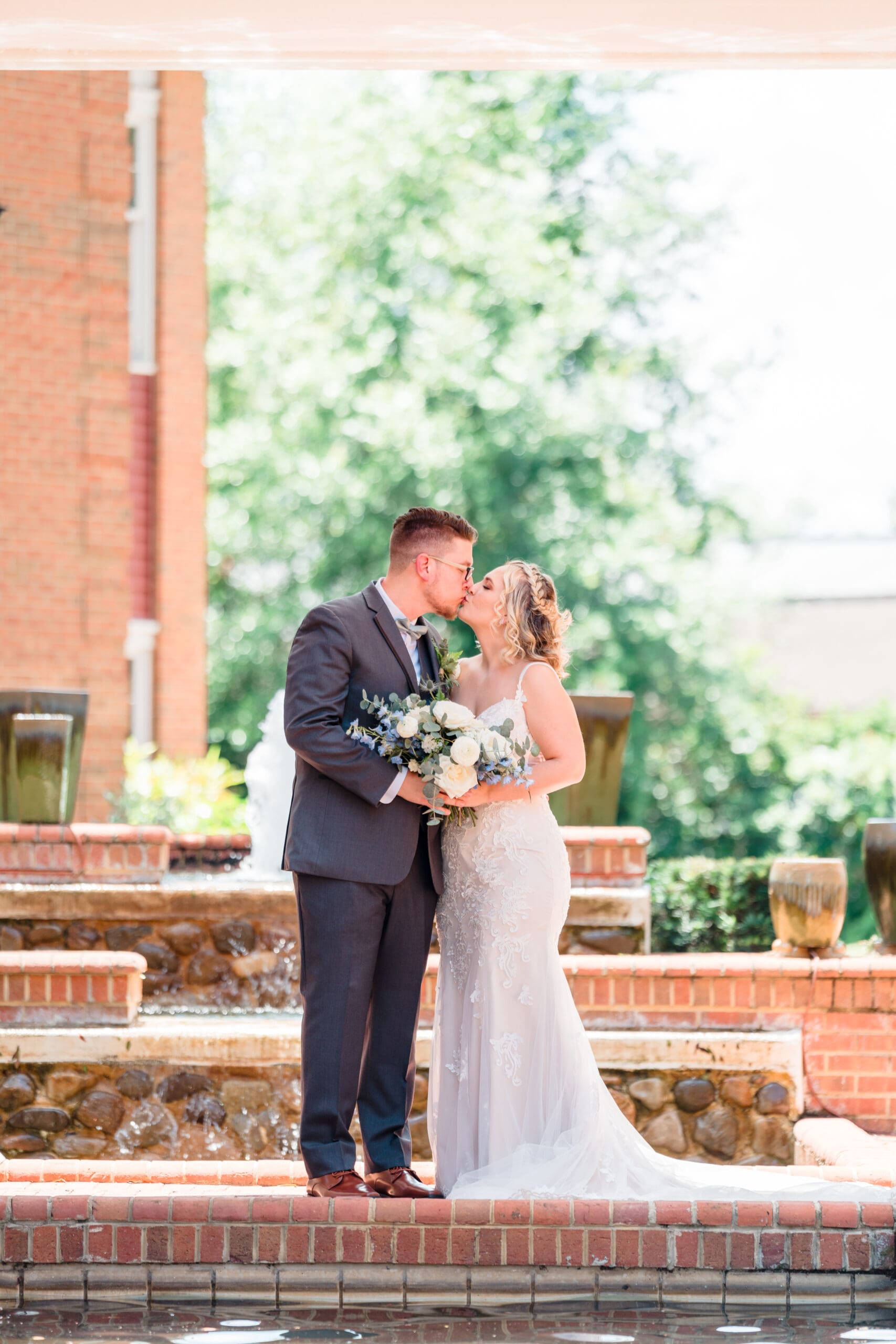 Captivating moment captured by Jerzy Nieves Photography, as the groom dips the bride for a romantic kiss in a picturesque brick courtyard, radiating timeless love and elegance