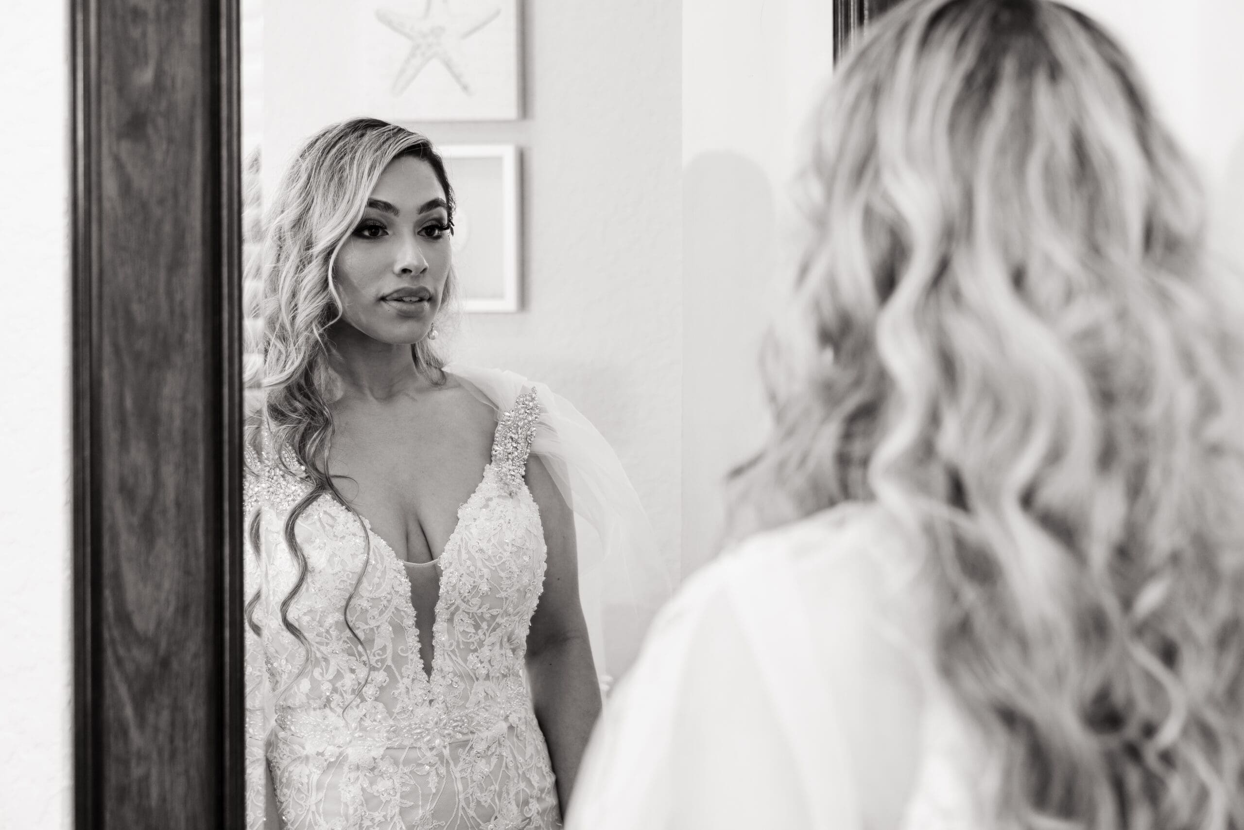 Black and white photo of Jenn admiring her final bridal look in the mirror of the bridal suite at the Crystal Ballroom.