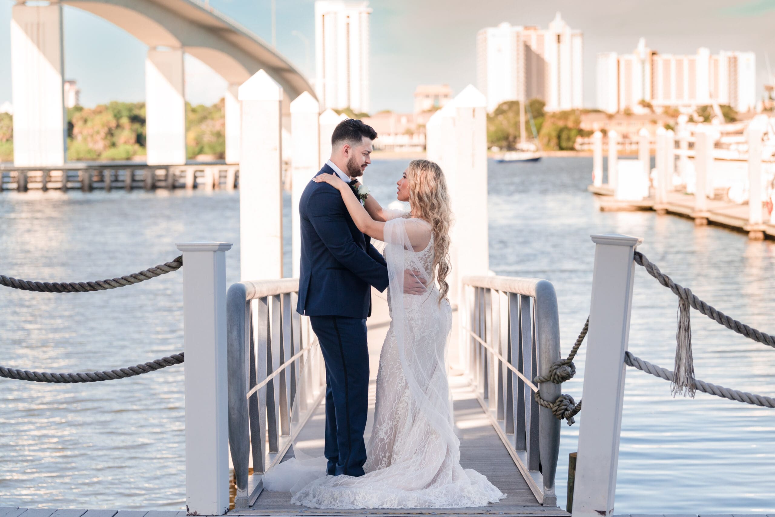 Jenn and Jazer embracing on the dock at Sunset Harbor, with ocean in the background.