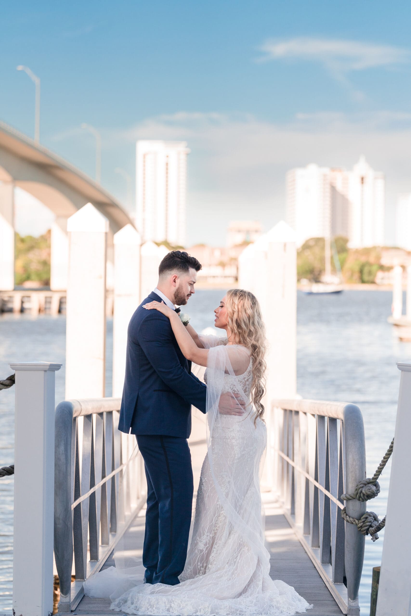 Jenn and Jazer embracing on the tall dock at Sunset Harbor, with ocean in the background.