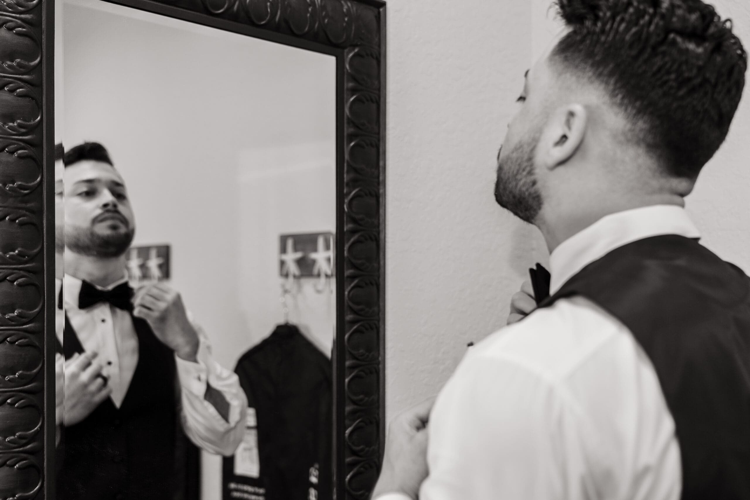 Jazer adjusting his tie in the mirror in black and white