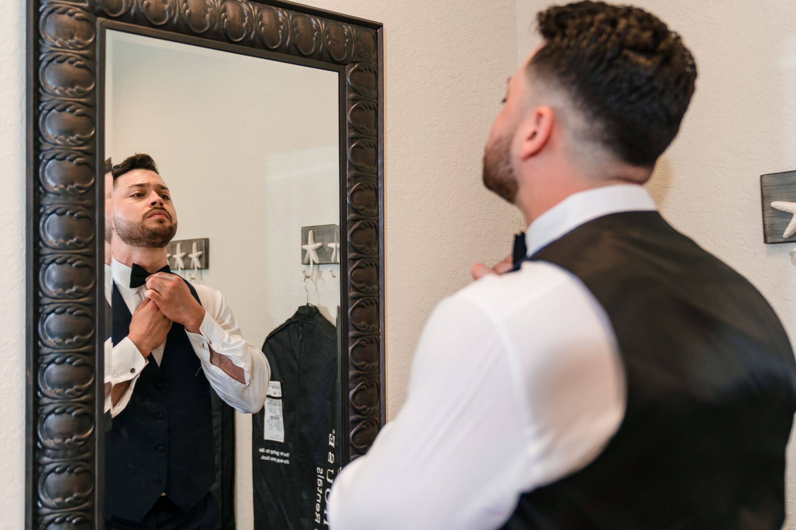 Jazer adjusting his tie in the mirror in black and white.