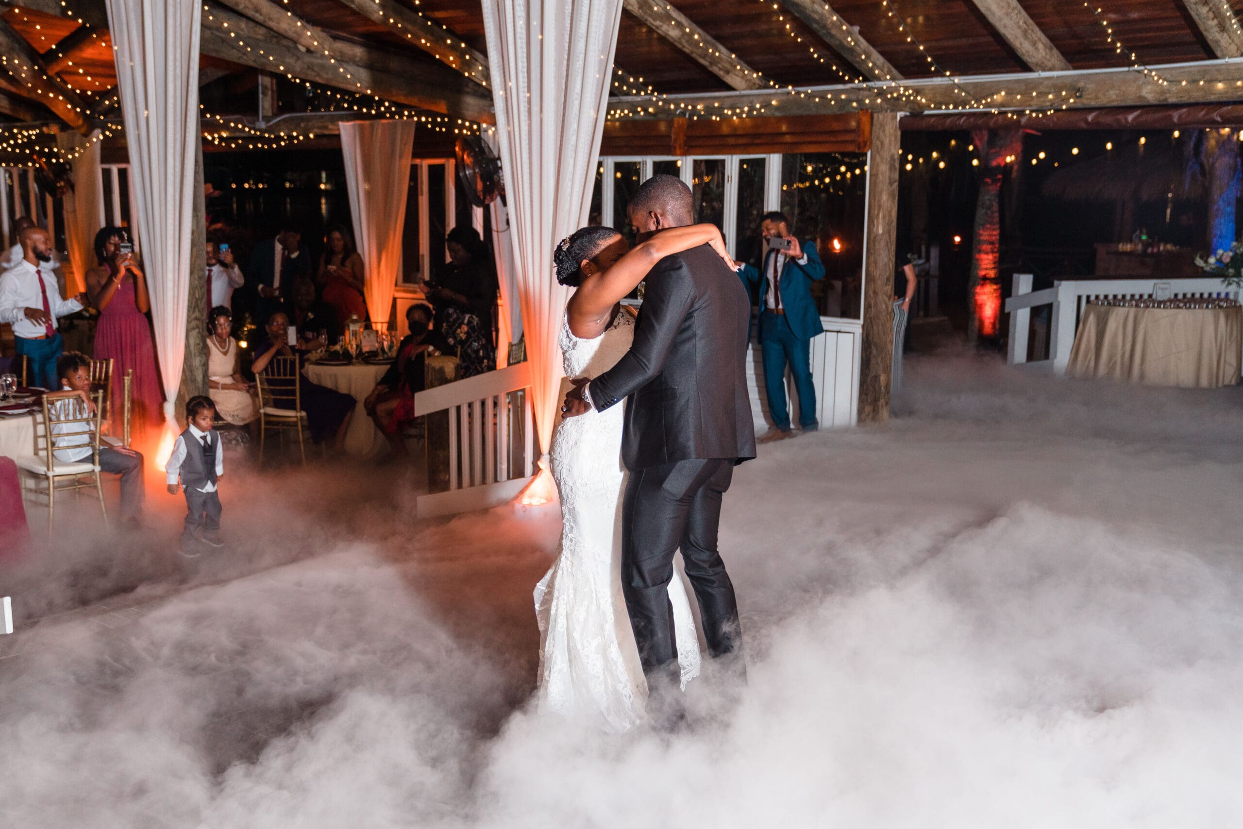 Wide shot capturing Kourtni and Jamie embracing each other amidst the fog-filled dance floor at Paradise Cove reception.
