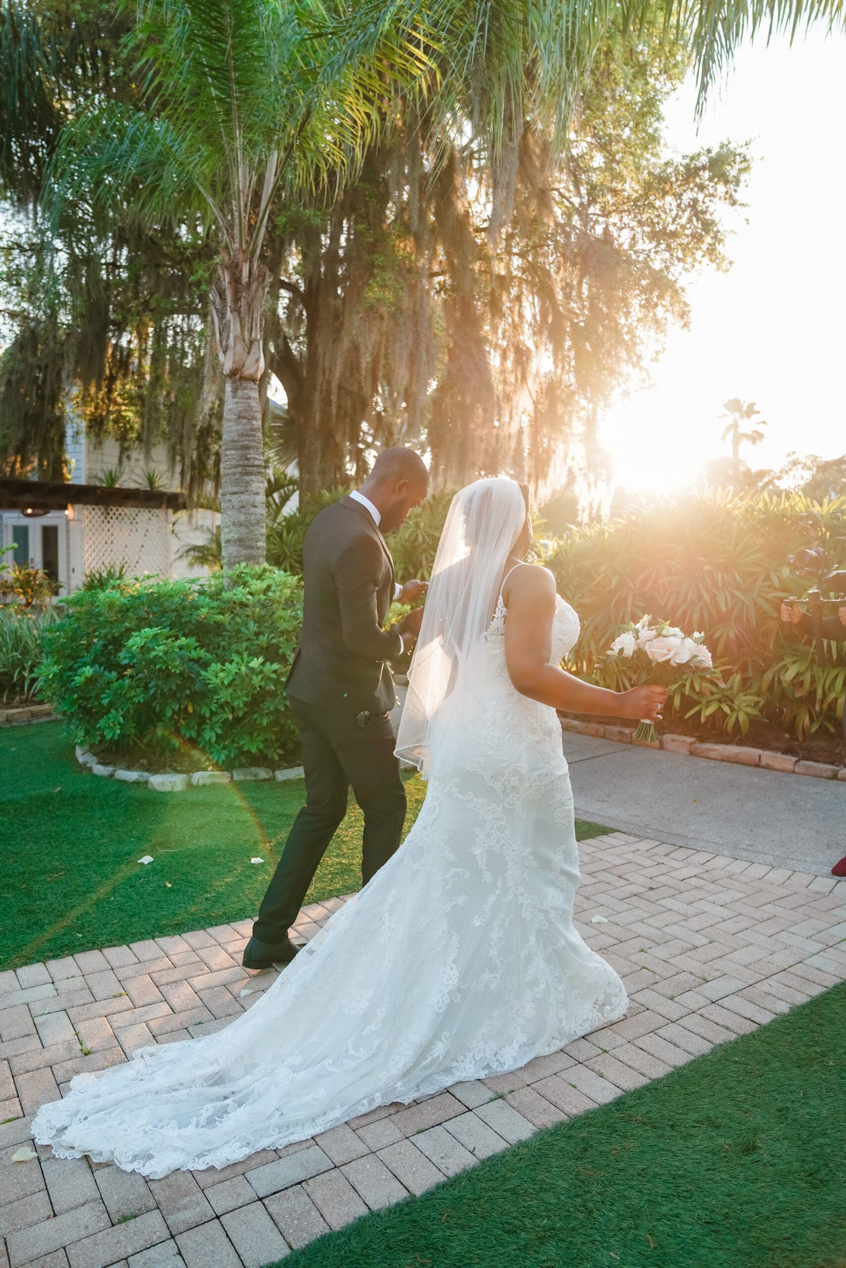 Unique tall shot capturing Jamie and Kourtni's final steps down the aisle at Paradise Cove, hand in hand, dancing with the sun setting behind them and the beauty of palm trees and nature in the background, showcasing Jerzy Nieves Photography's creativity.