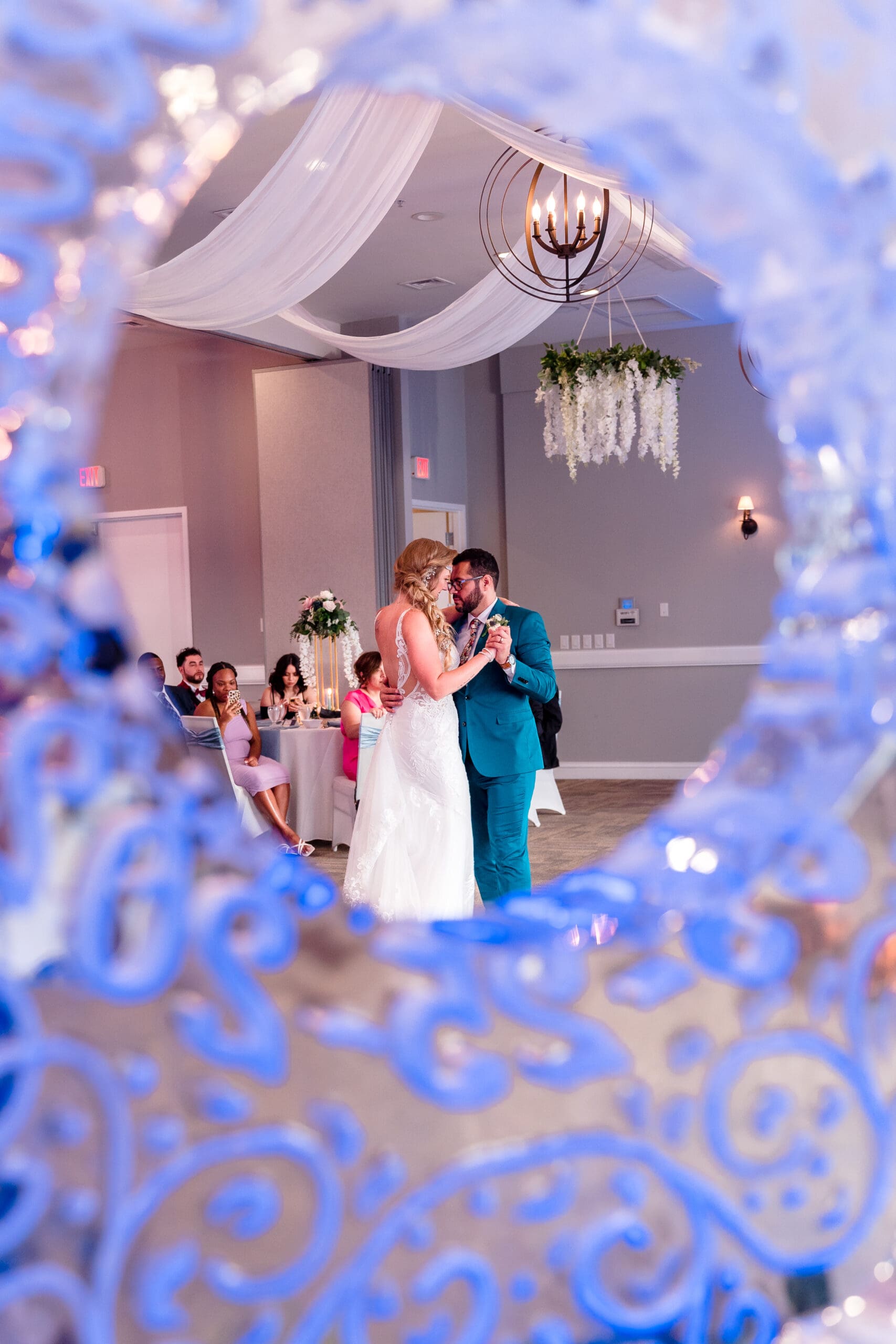 View of the couple's first dance through an ice circle decoration, framing the intimate moment.