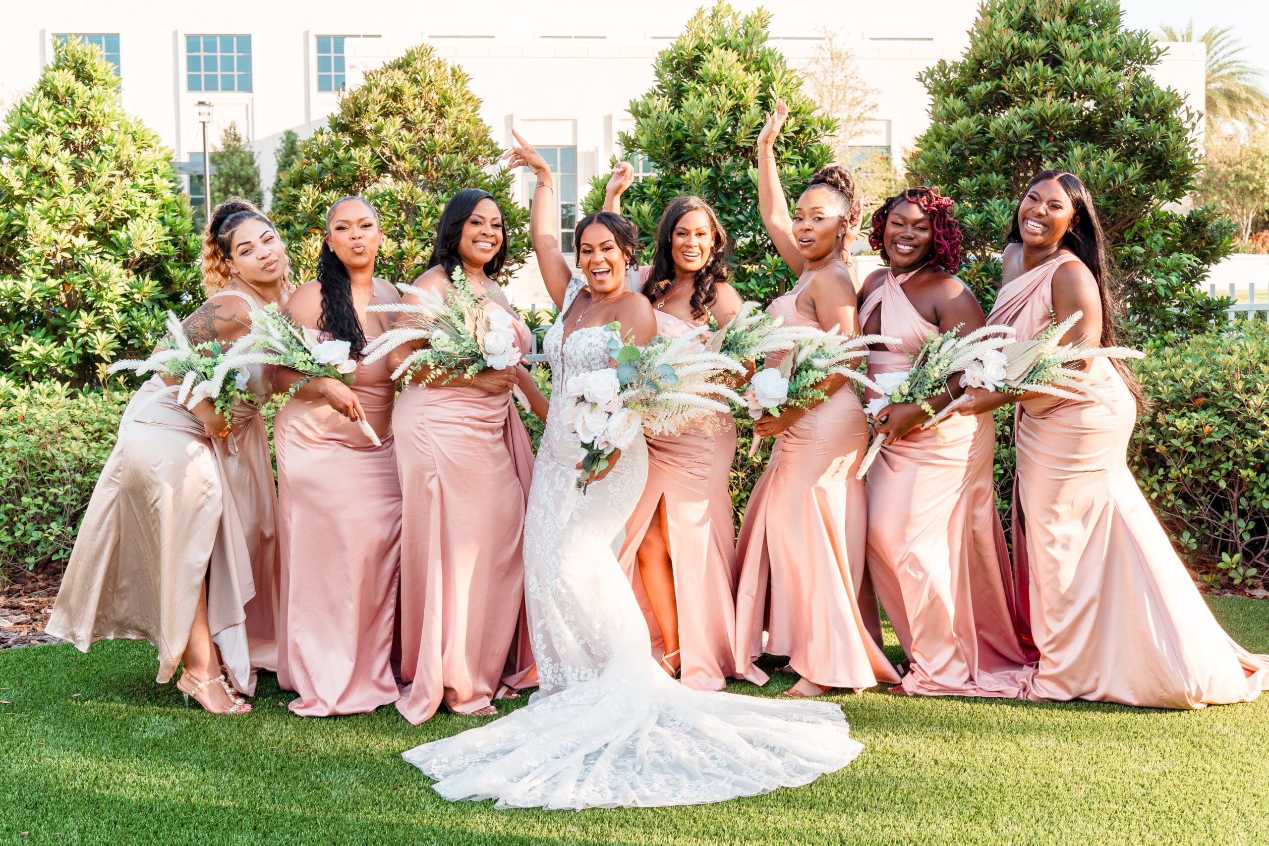 Lateisha and another set of bridesmaids in pink dresses posing together for a celebratory photo.