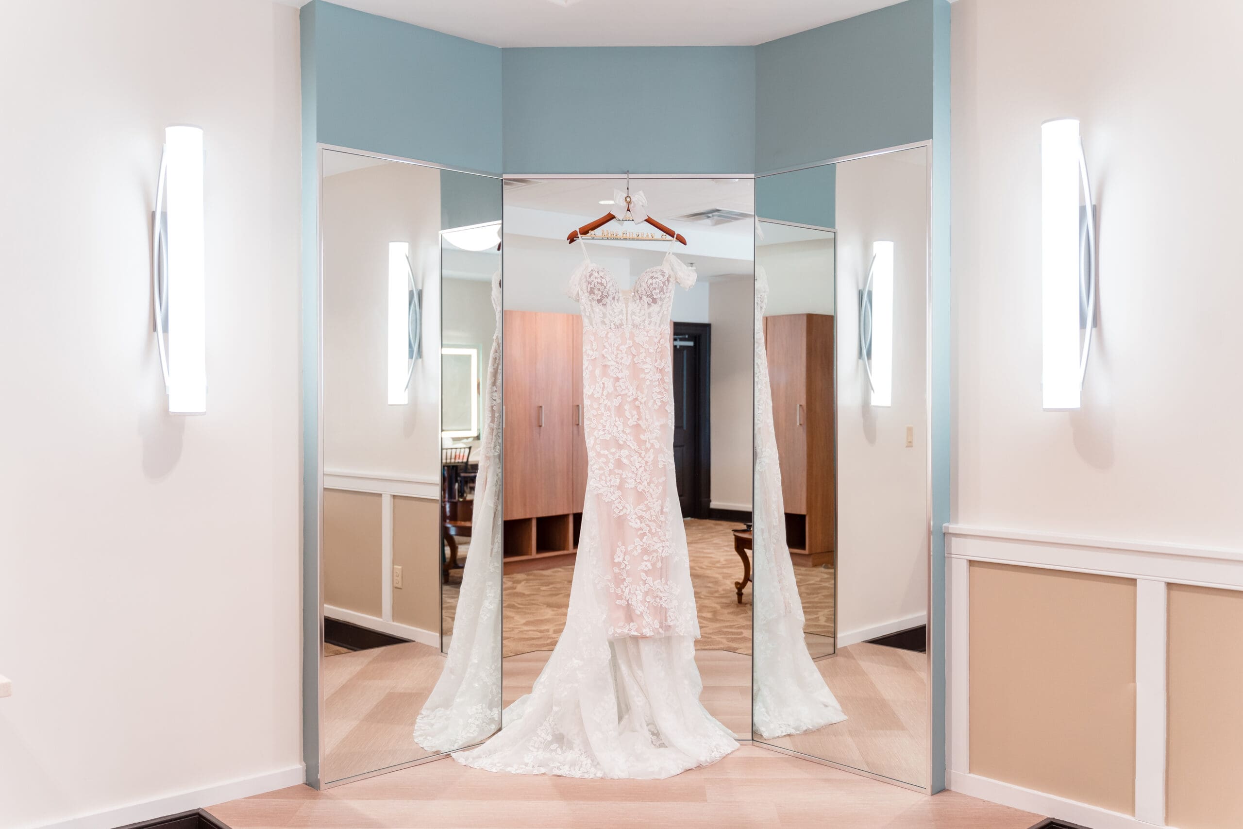 Lateisha's wedding dress hanging elegantly in front of a tri-fold mirror.