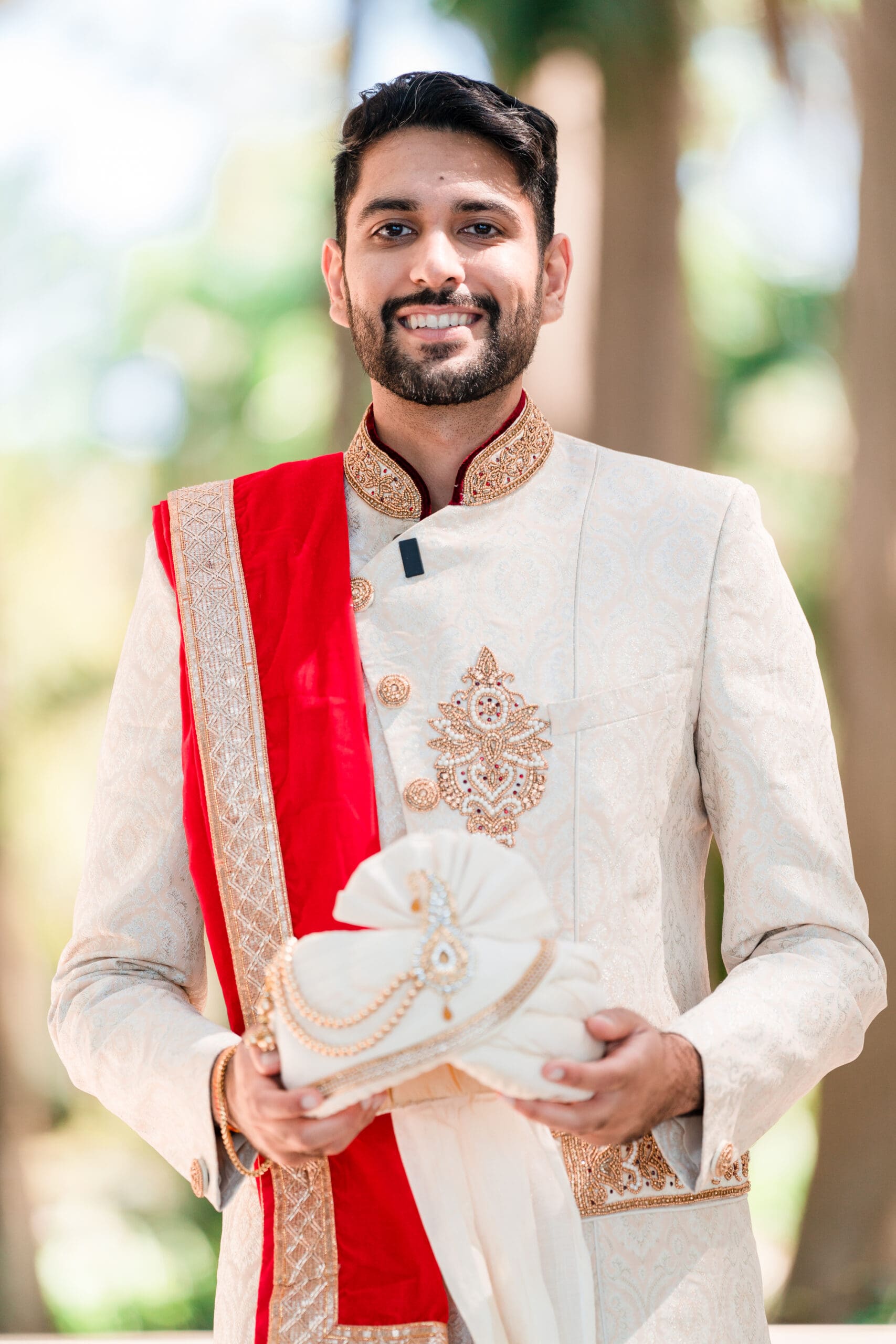 Rahul smiling while holding his traditional Indian wedding headpiece