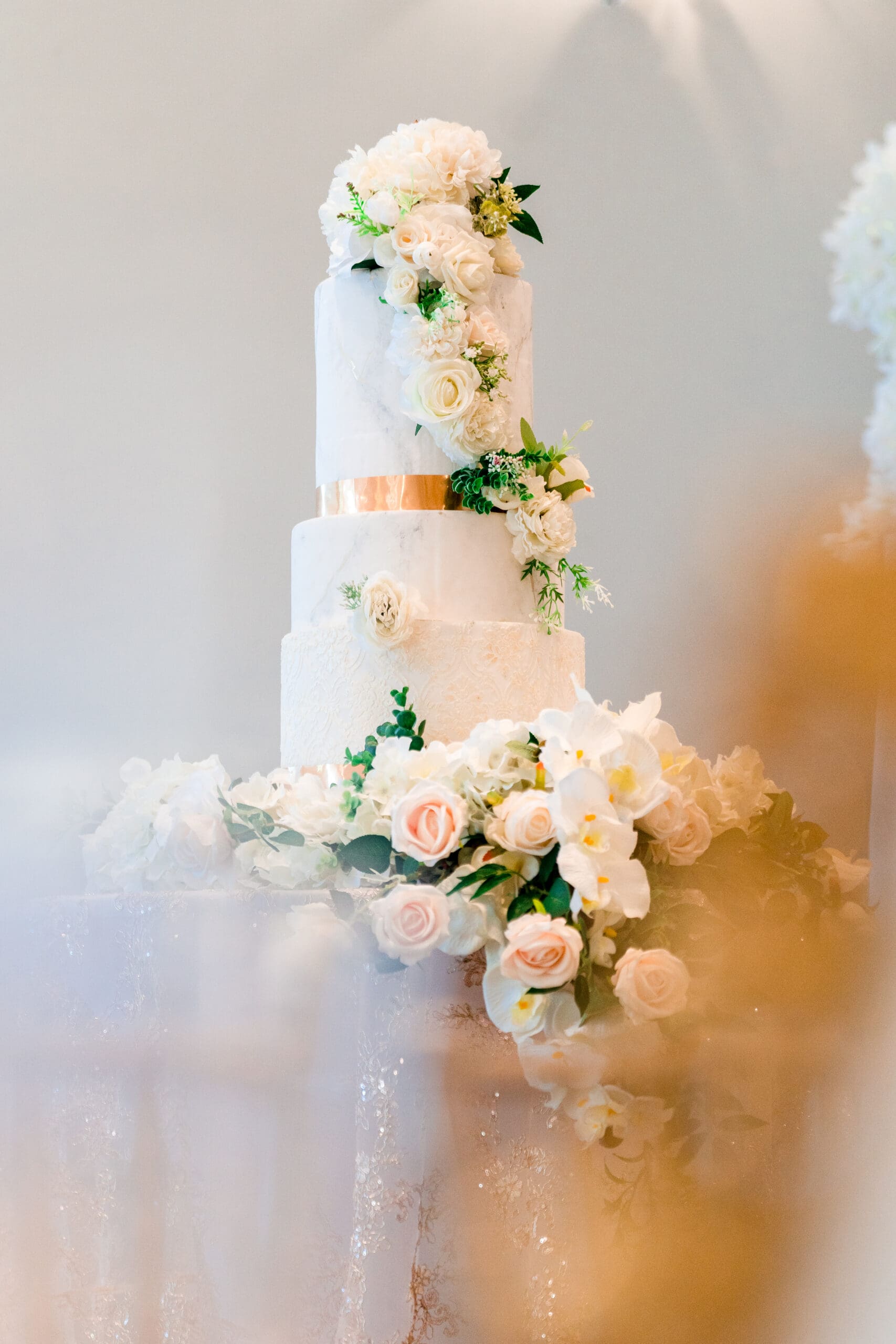 Four-tier wedding cake adorned with real and edible flowers