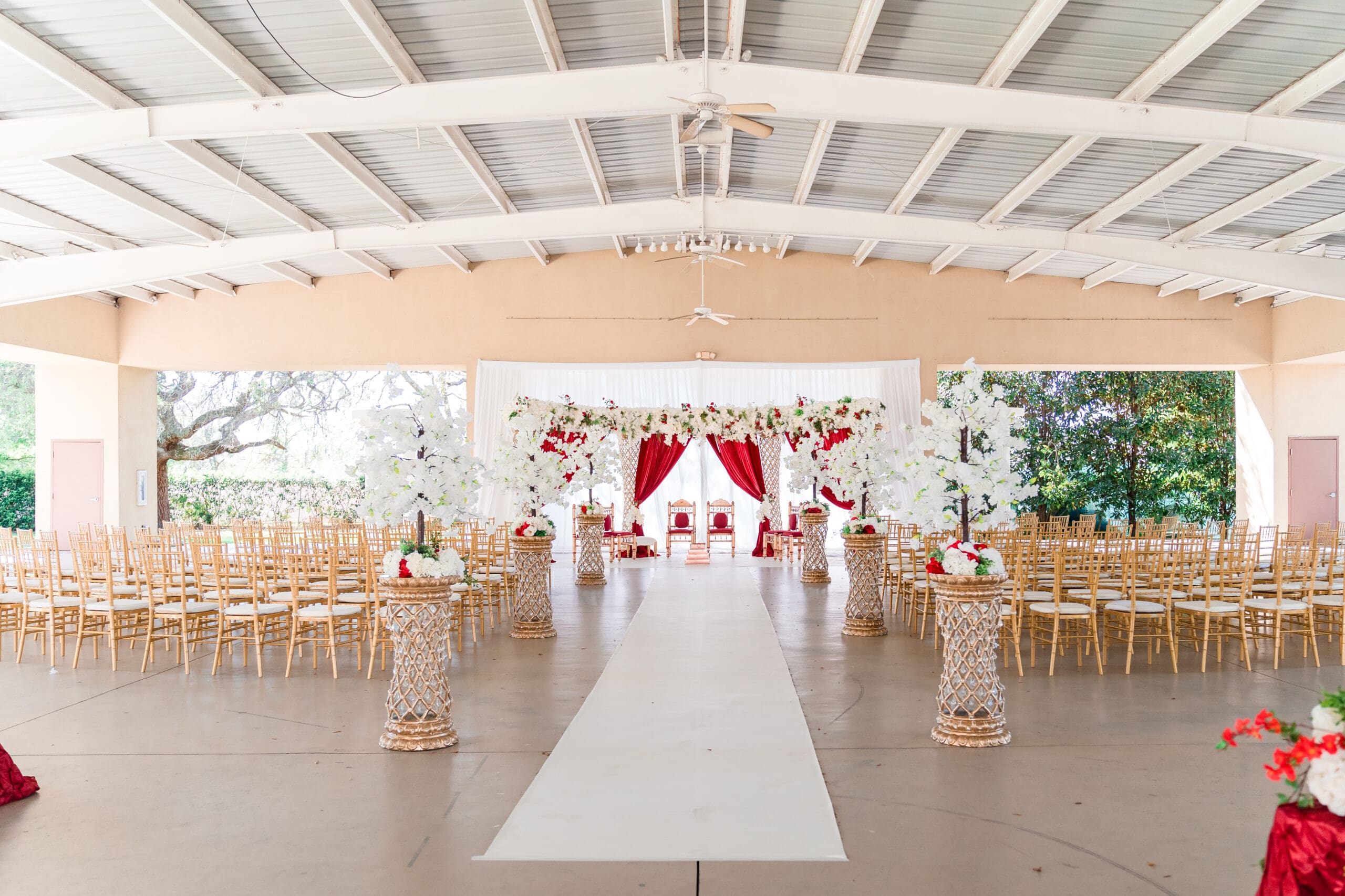 Ceremony area and altar adorned with red drapes and white flowers at Kraft Azalea Gardens