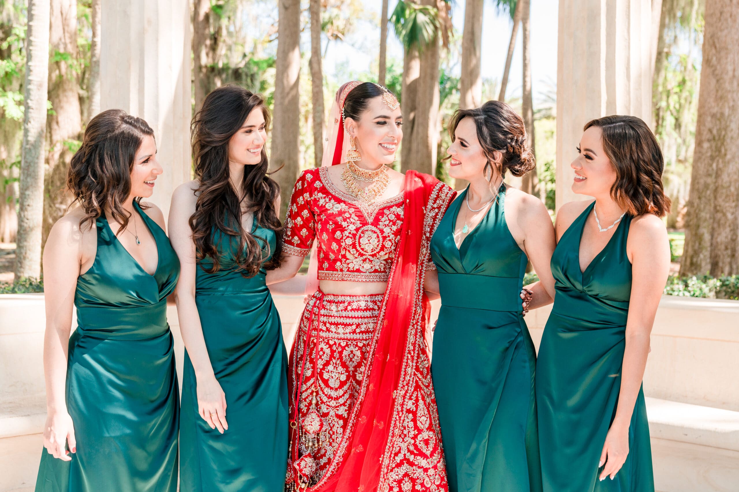 Bride Sabrina and her bridesmaids share a moment, looking at each other in a lively pose at Kraft Azalea Gardens.