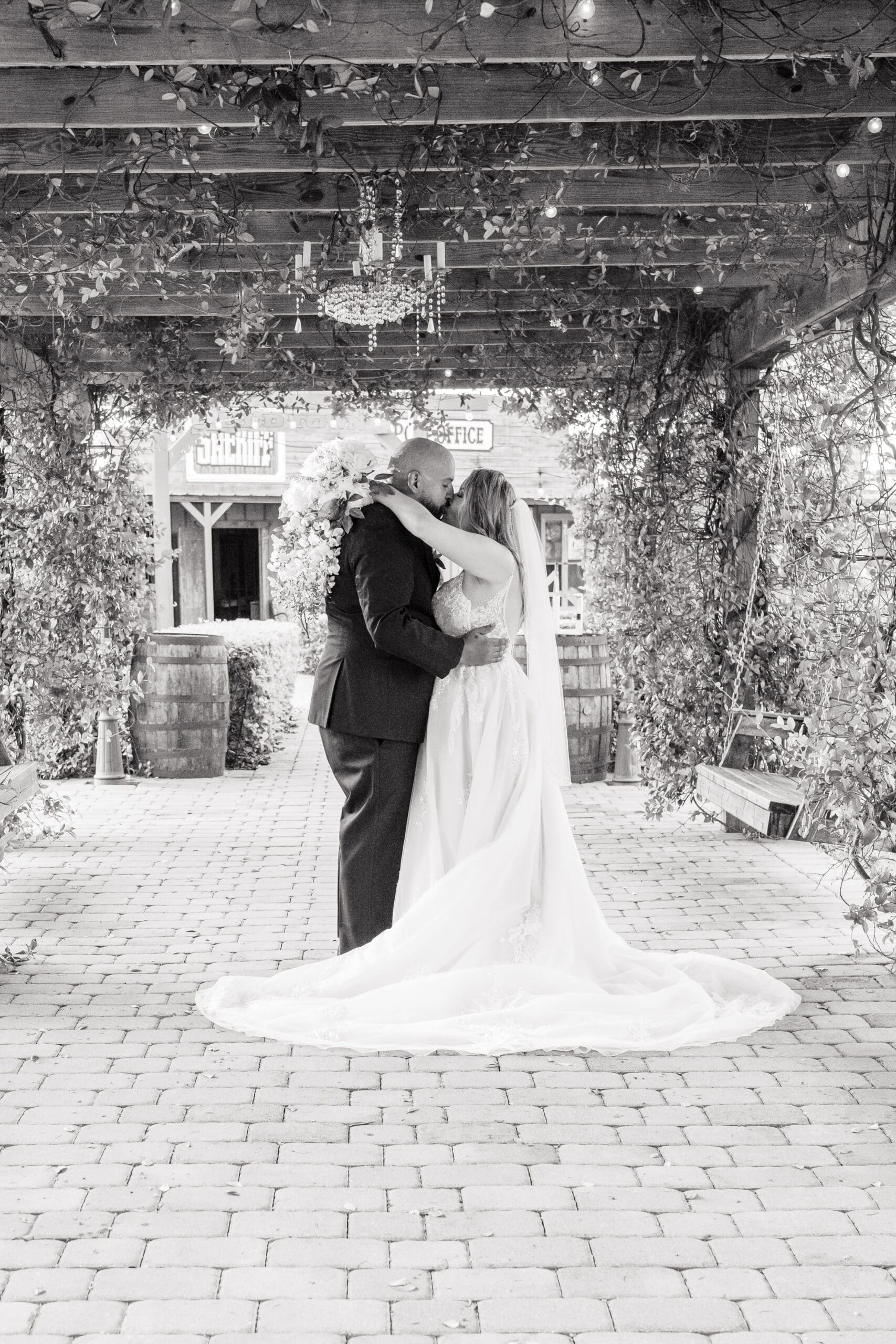 Newlyweds Kissing Under Wooden Walkway at Hidden Barn Venue