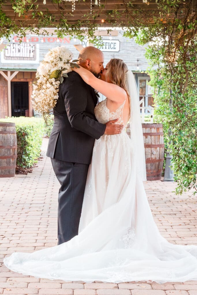 Newlyweds Kissing Under Wooden Walkway at Hidden Barn Venue