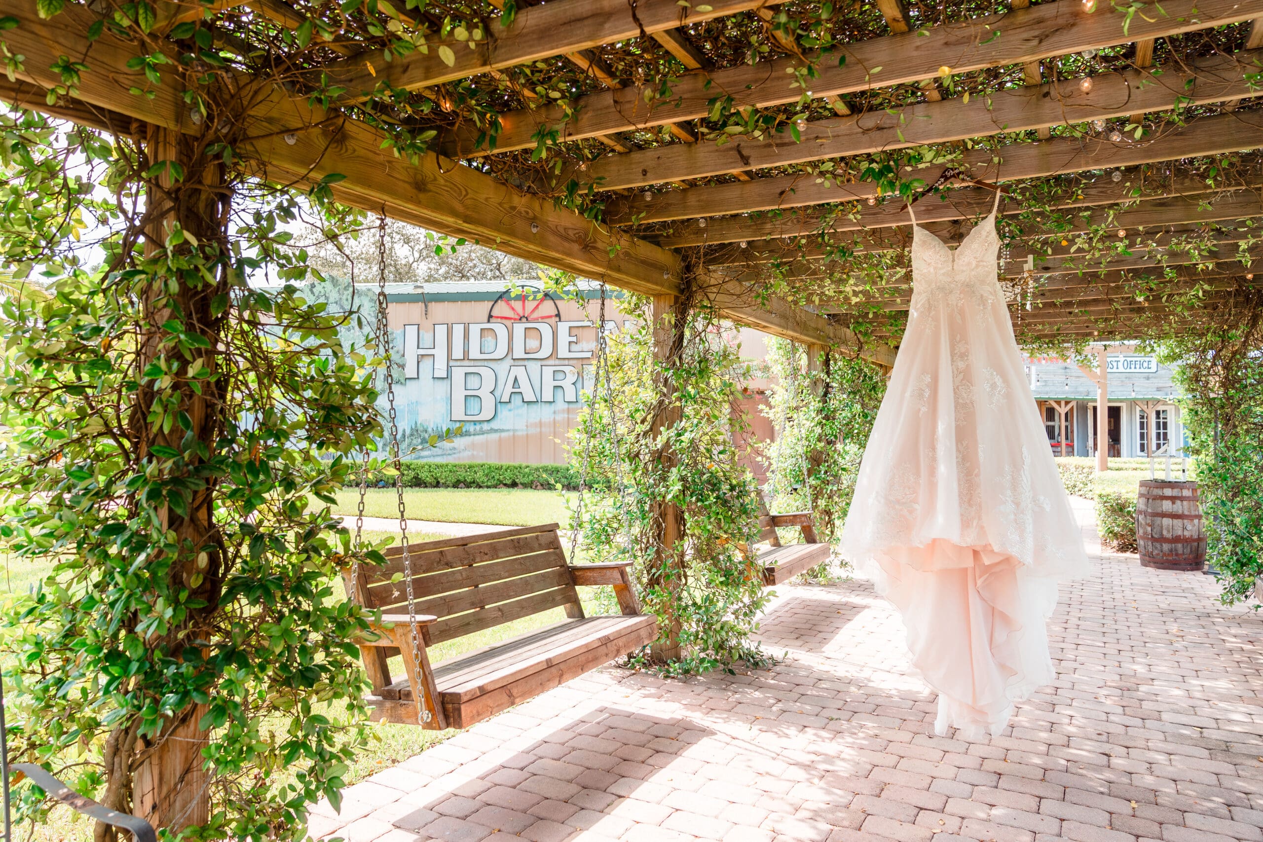 Bride's Wedding Dress Hanging at Hidden Barn Venue with Sign in Background