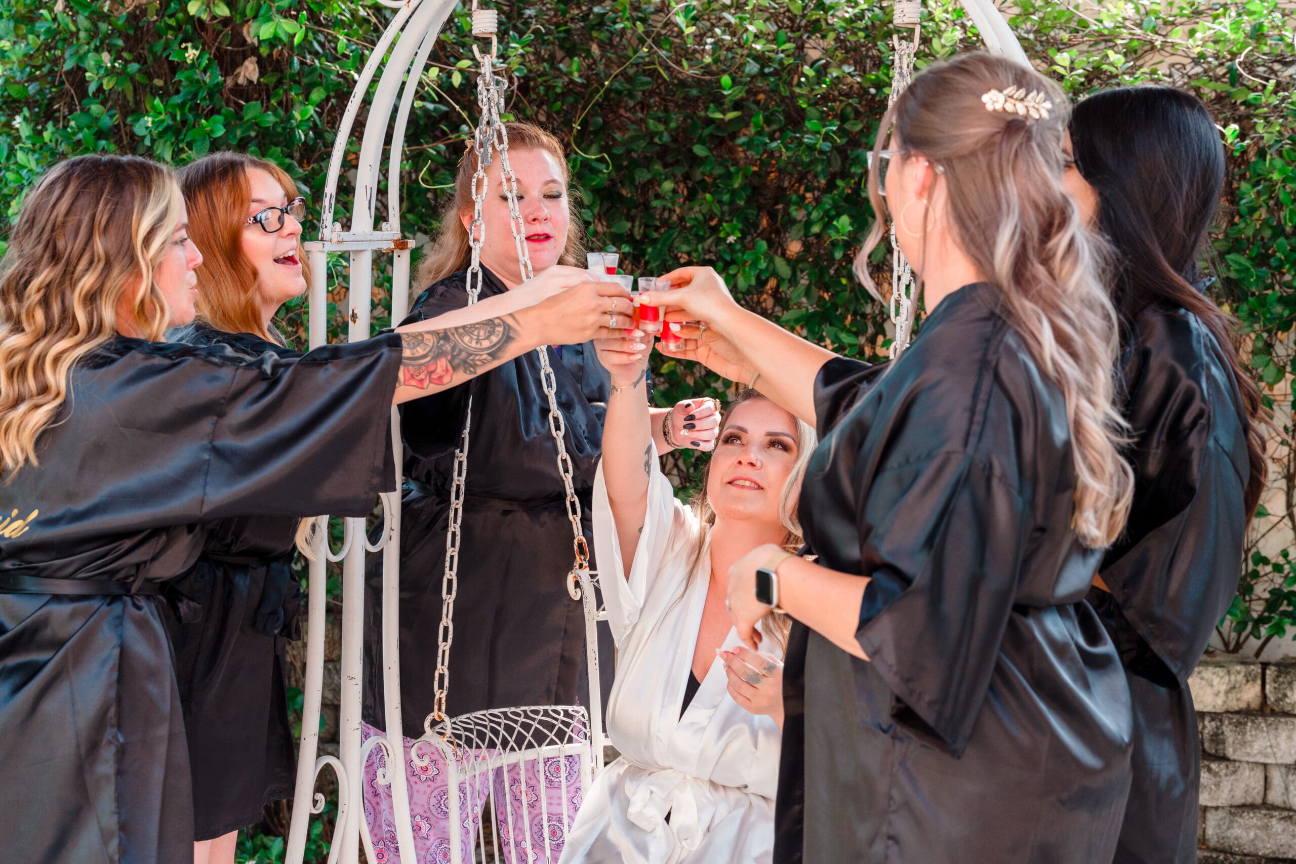 Bride and bridesmaids toasting with glasses touching in the garden
