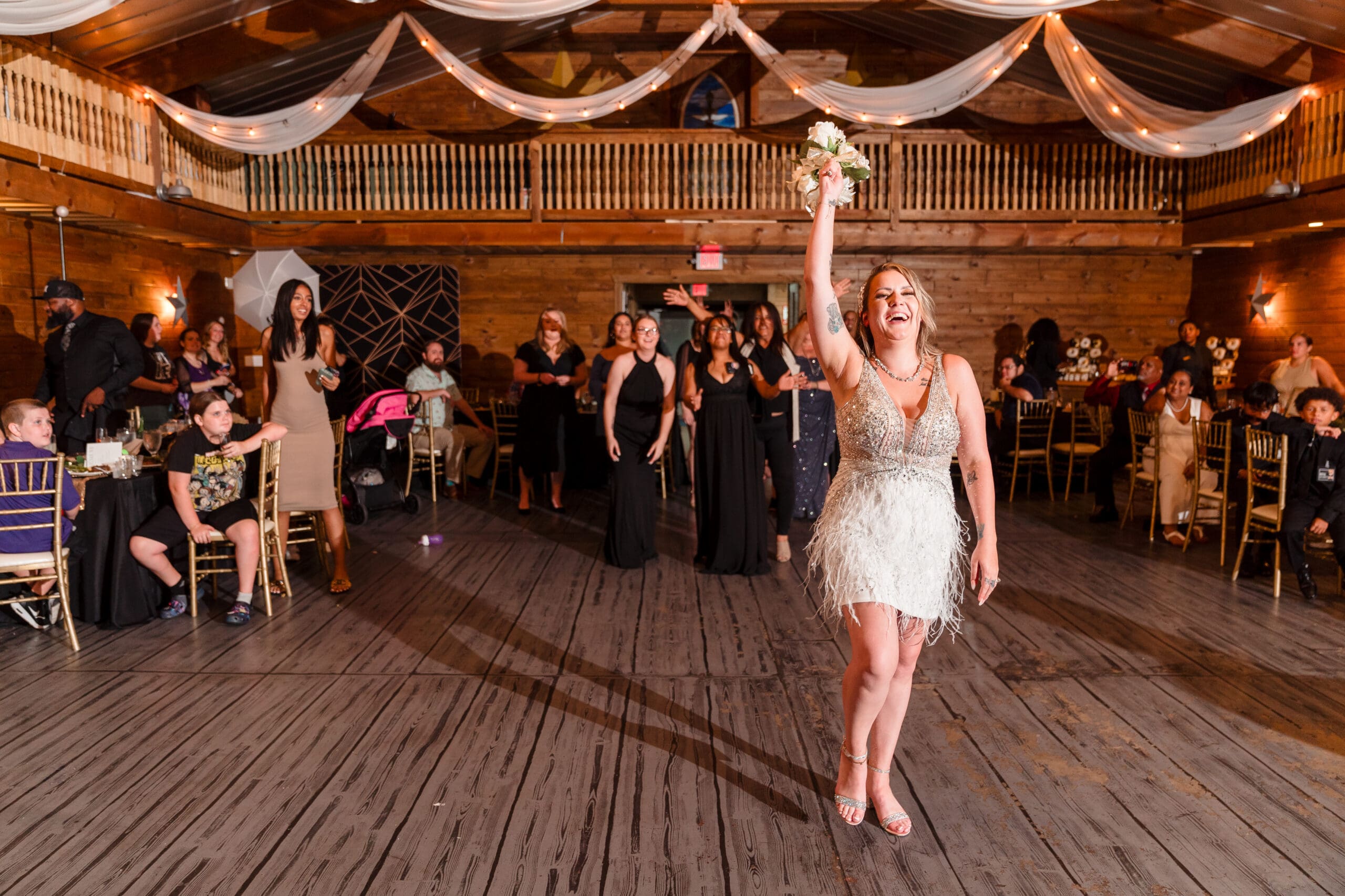 Taylor tossing her bouquet over her back towards bridesmaids and guests in the Hidden Barn Celebration Area, Apopka