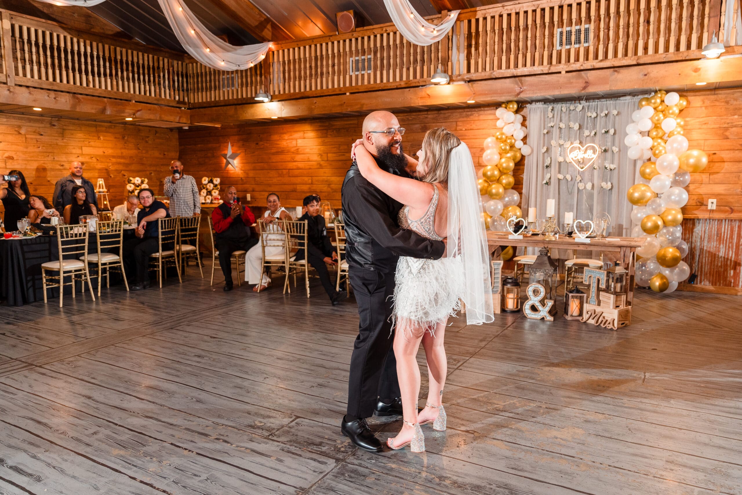 Taylor and David sharing their first dance as a married couple, gazing into each other's eyes, surrounded by elegant decorations at the Hidden Barn