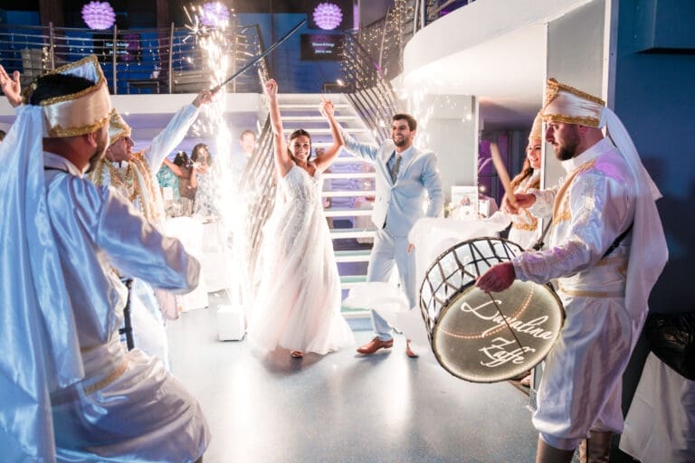 Cultural wedding couple at the bottom of stairs, band in traditional Indian attire playing drums, sparklers lighting their arrival.