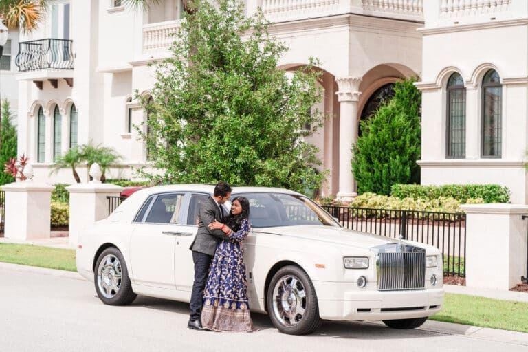 Newlyweds leaning against their Rolls Royce, gazing lovingly into each other's eyes.