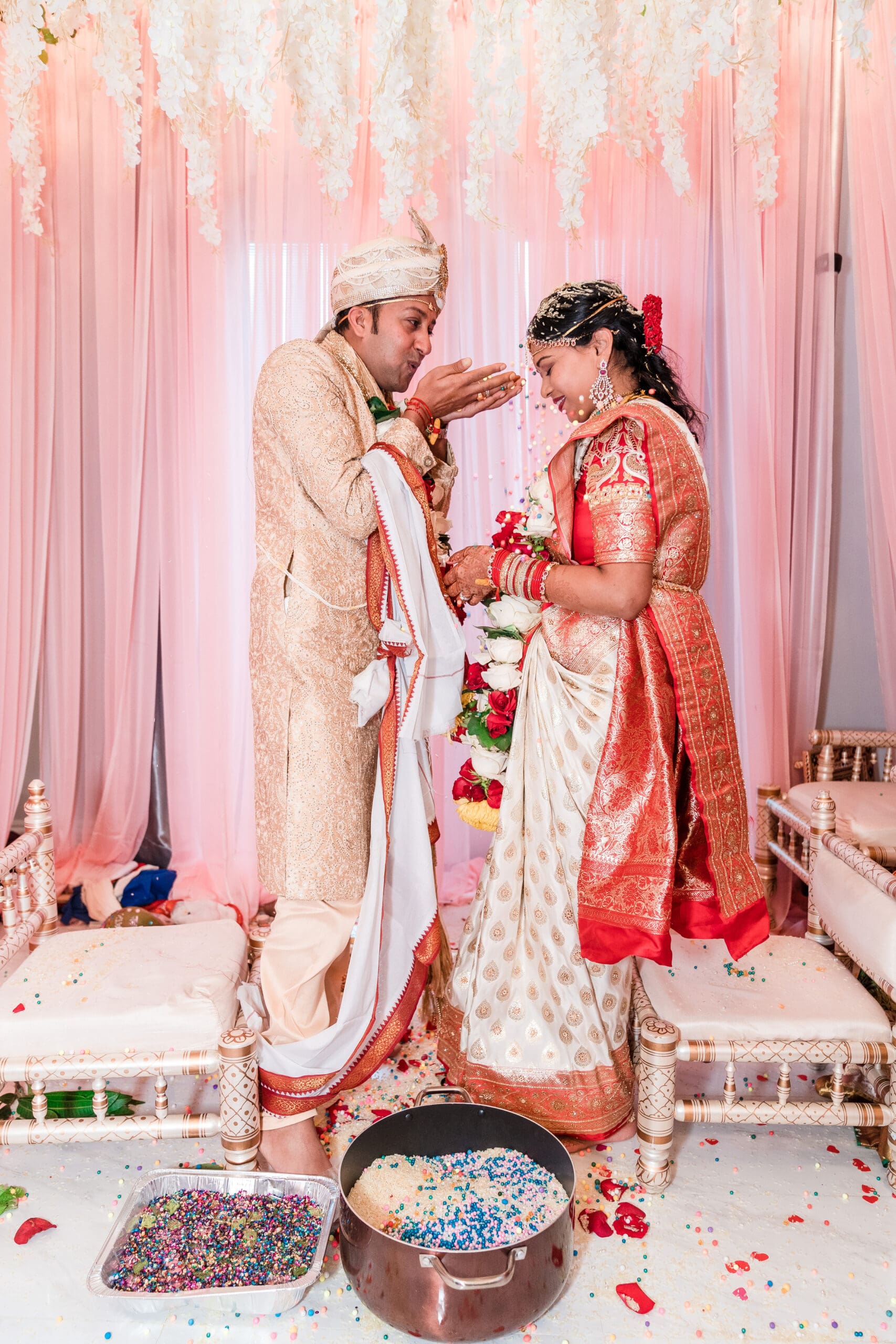 Couple adorned in traditional attire surrounded by cultural decorations - cultural wedding photography