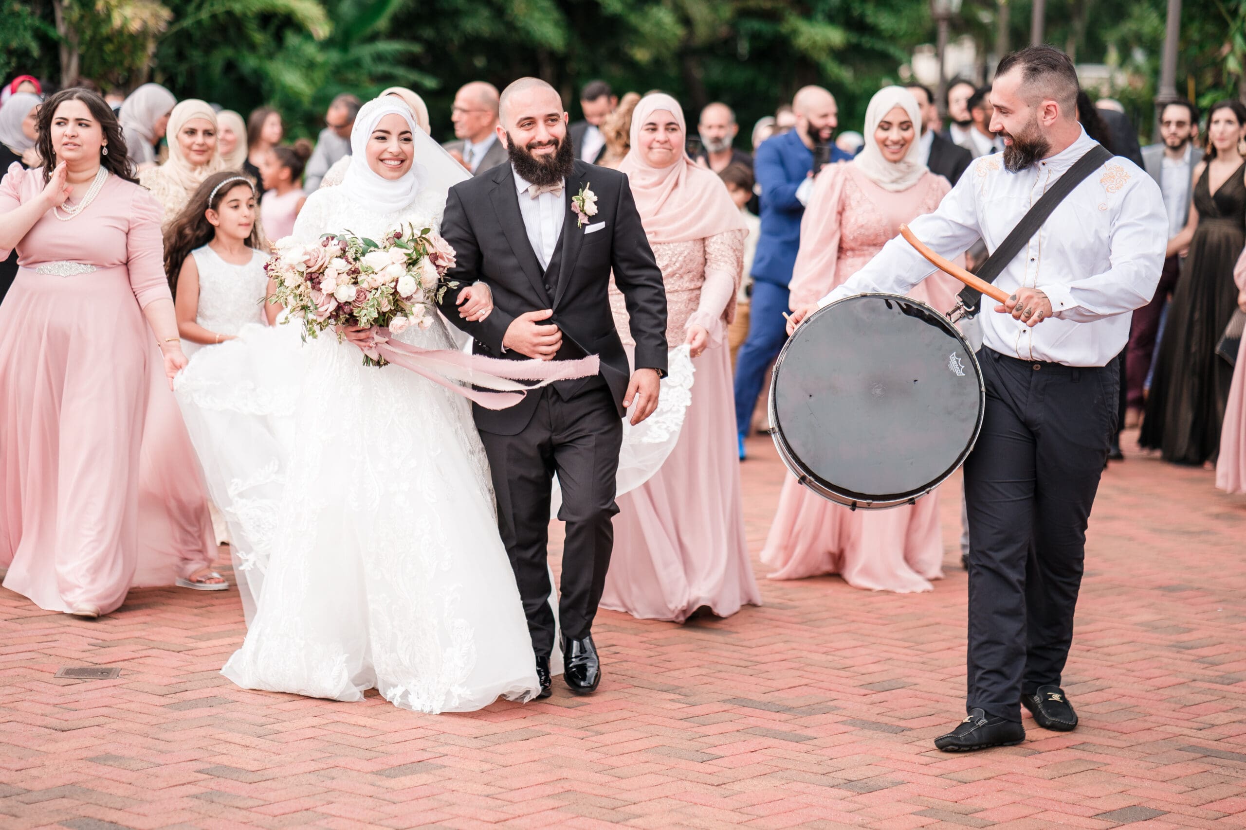 Couple leading a parade with drum players and guests walking behind them in a joyous celebration - cultural wedding photography