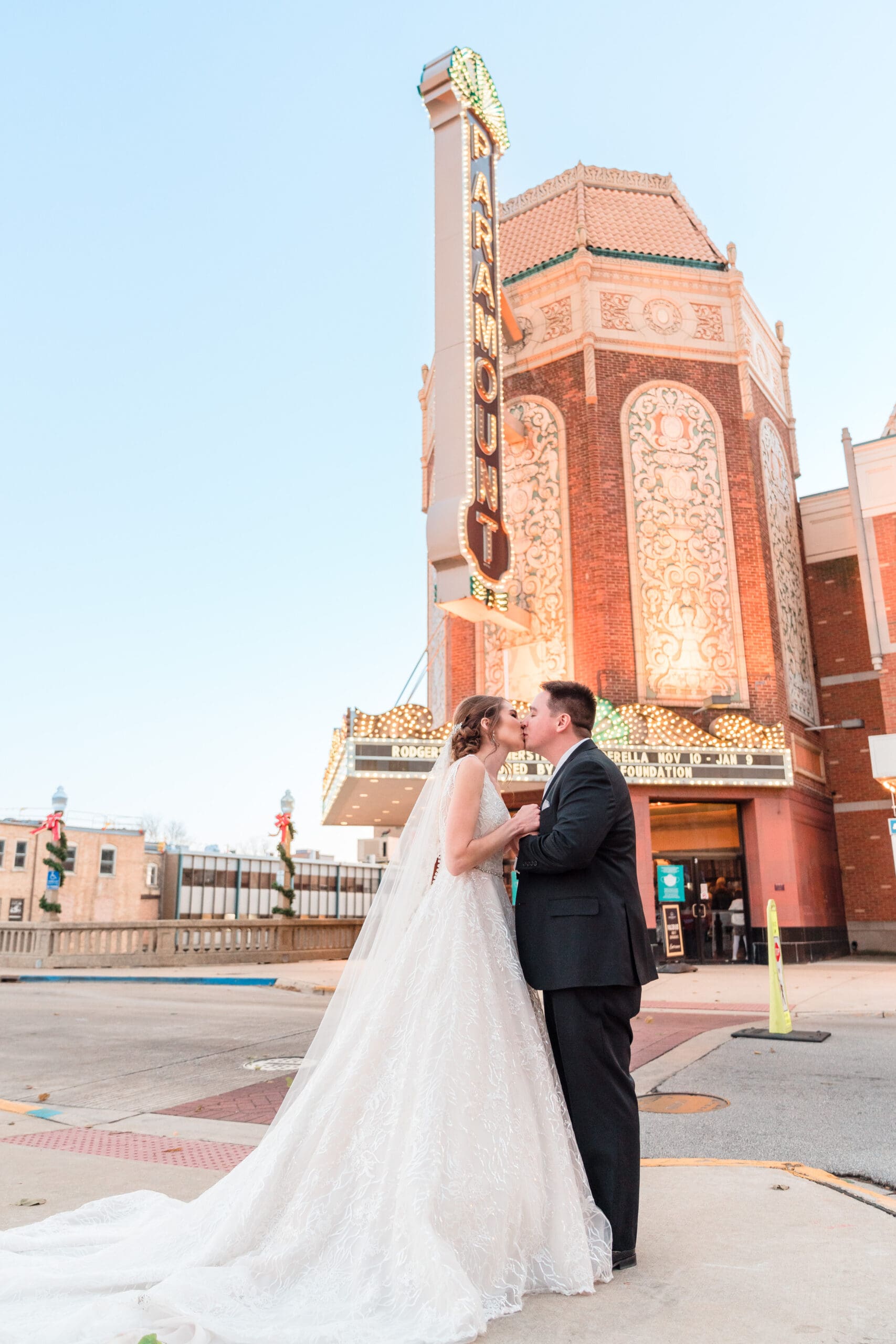 Iconic moment in front of Paramount Theater: Couple shares a passionate kiss with the iconic Paramount sign visible in the background, capturing the essence of their love against the backdrop of Denver, Colorado