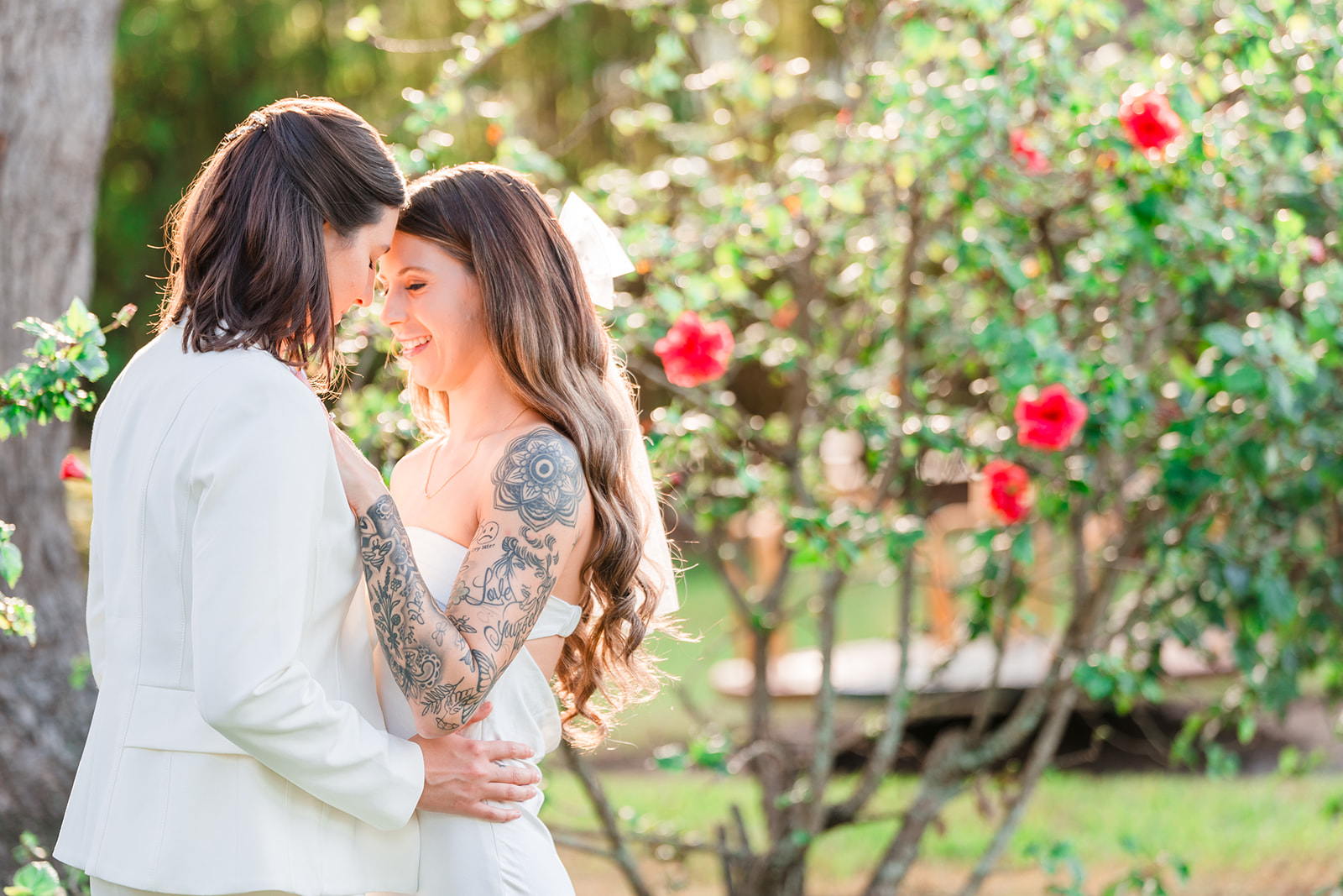 Two brides embrace each other against a stunning natural backdrop, illuminated by perfect lighting, in a captivating photograph.