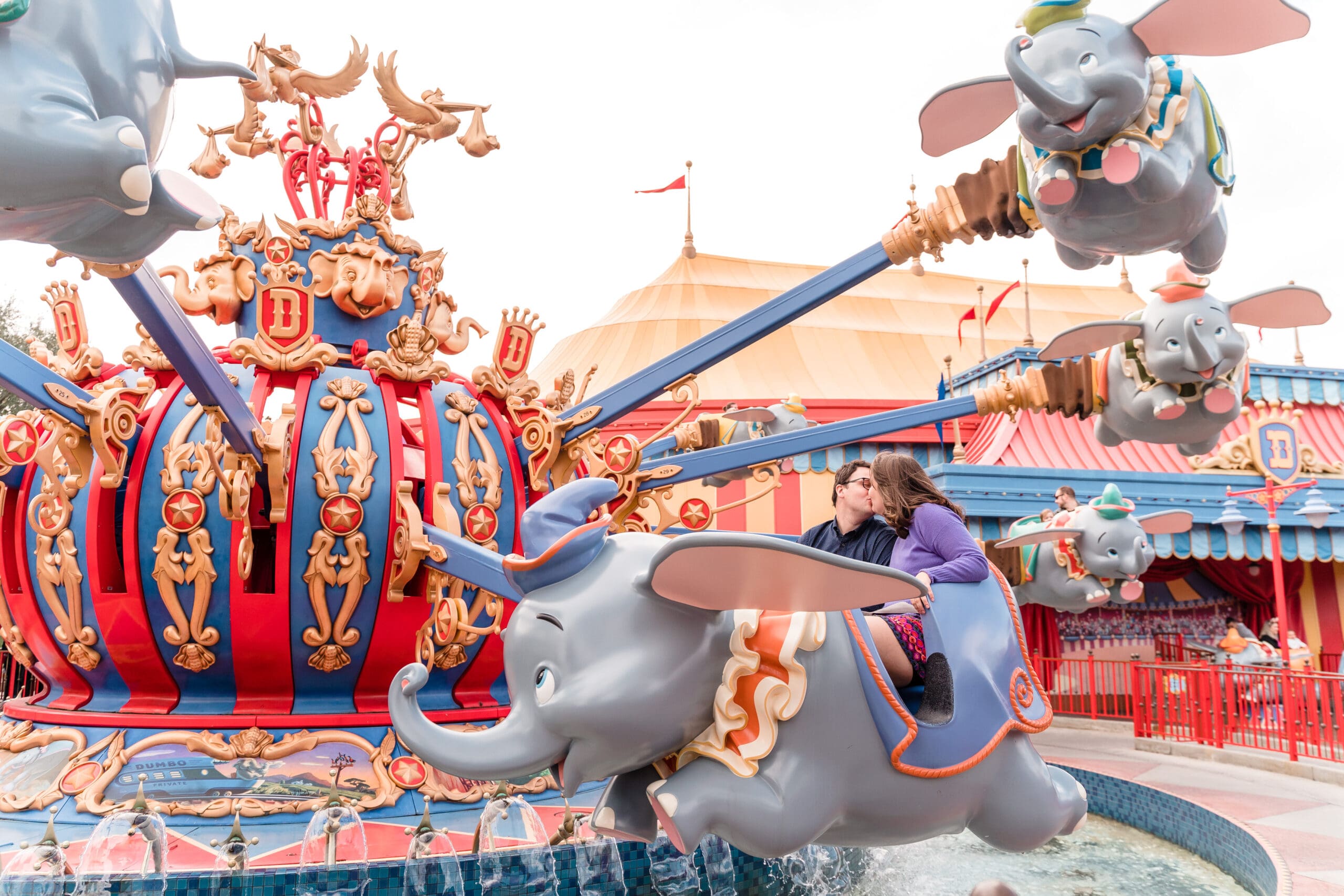 Couple kissing on the Dumbo ride, capturing their love at Disney in this classic ride.