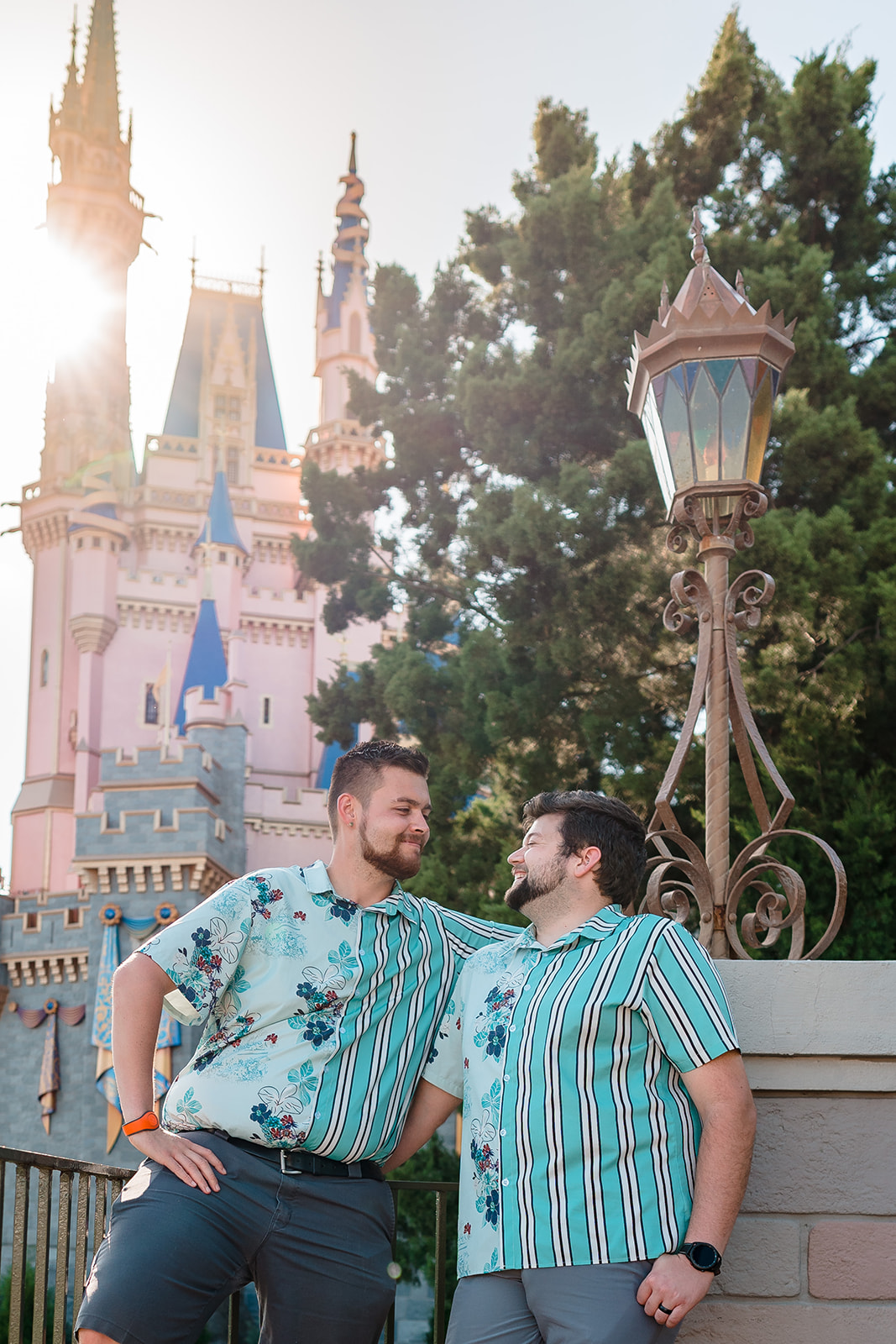 A close-up of two grooms smiling at each other with the iconic Disney castle in the background, capturing an intimate moment of love and joy at Magic Kingdom.