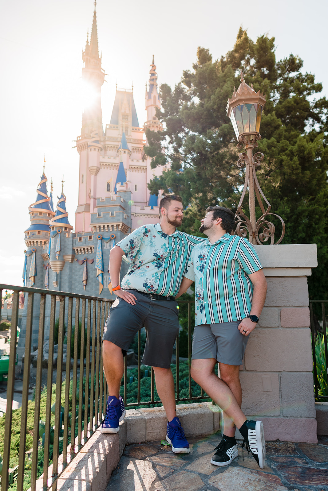 Two grooms smile at each other with the iconic Disney castle in the background, capturing a perfect moment of love and joy at Magic Kingdom.