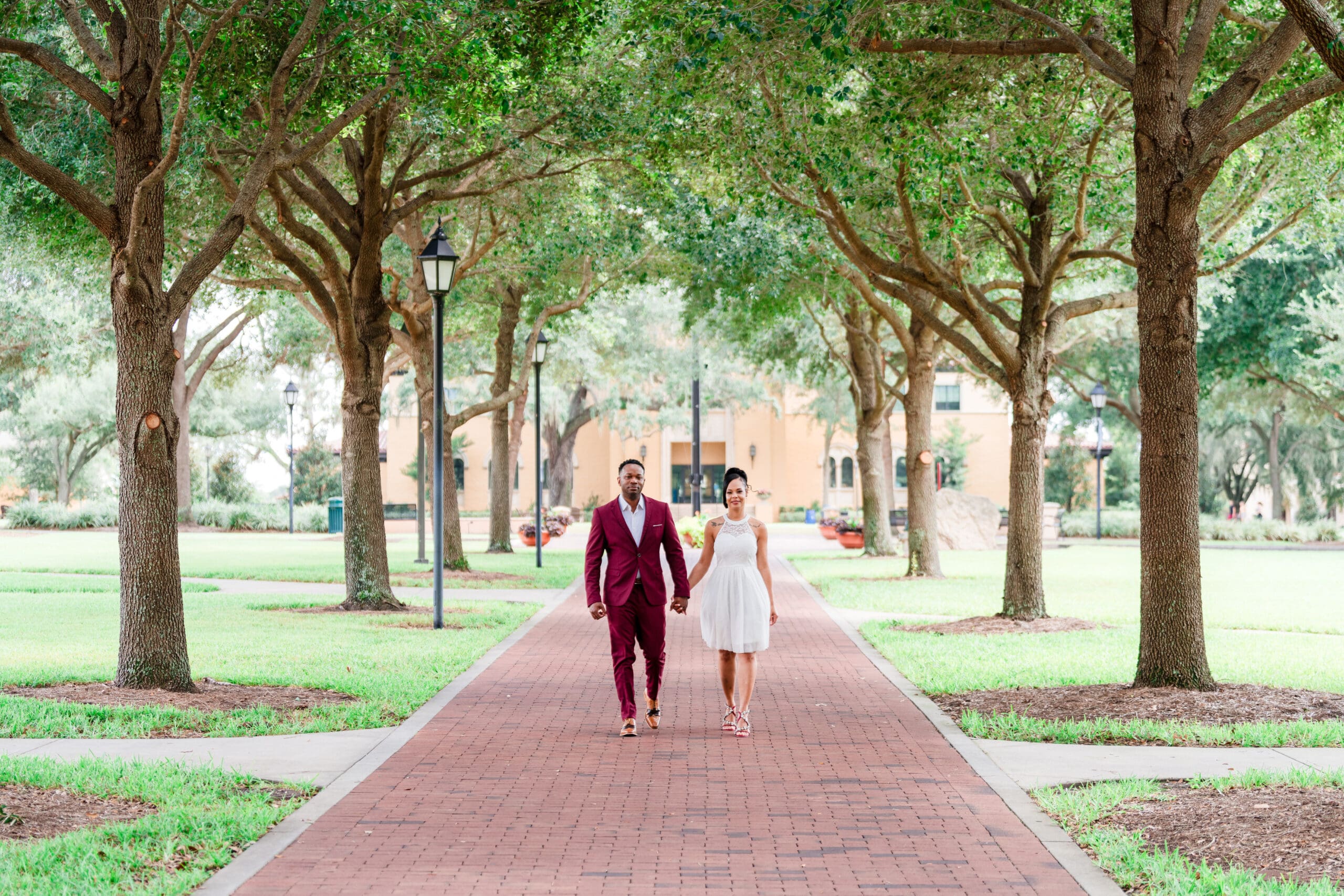 Engagement photo of couple holding hands, walking down the campus of Rollins College in Winter Park, FL, showcasing their unique story.