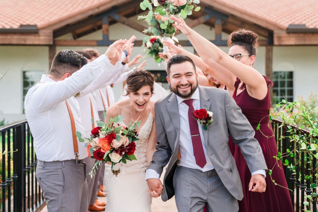 Bridal party forming a tunnel with hands raised as the newlyweds make their grand exit under it at Sterling Event Venue.