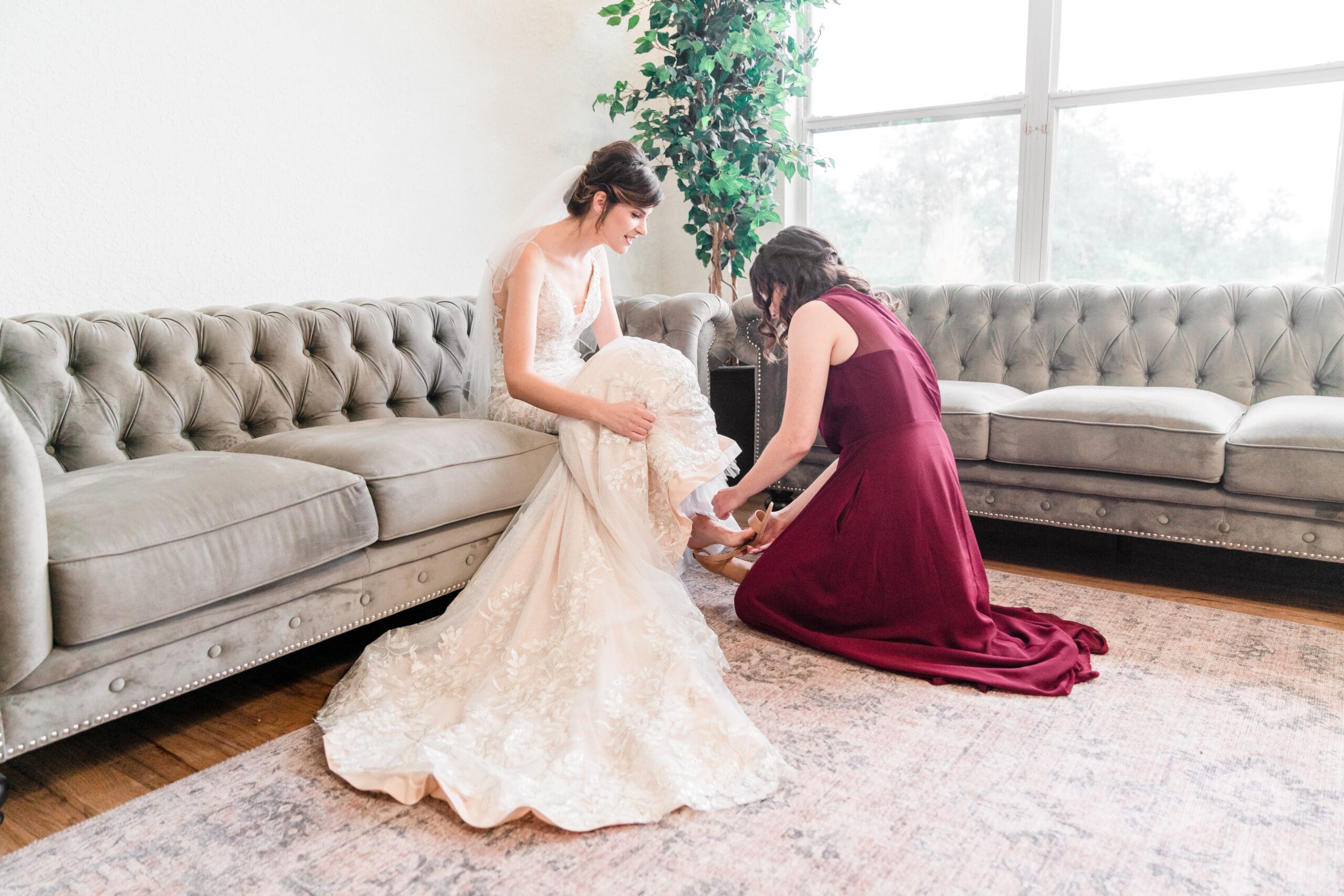 A bridesmaid helping Bethany put on her heels in the bridal suite at Sterling Event Venue before the wedding.