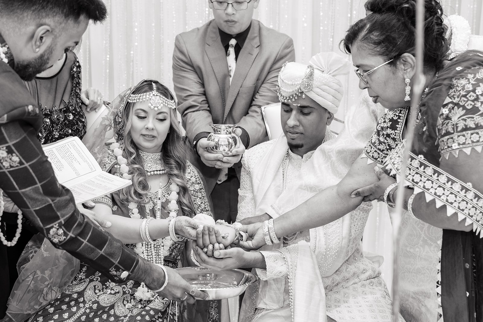 Black and white photo of Ravin and Nicole hand in hand during their Indian wedding ceremony.