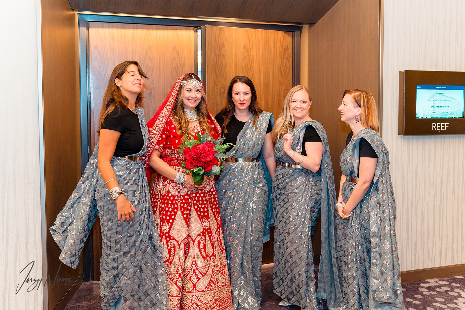 Nicole and her bridesmaids, dressed in traditional Indian wedding attire, smile for the camera in the lobby of Disney Swan Reserve.