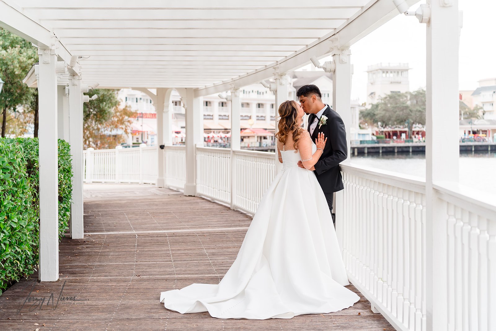 Ravin and Nicole kissing on the walkway by the water at Disney Swan Reserve.