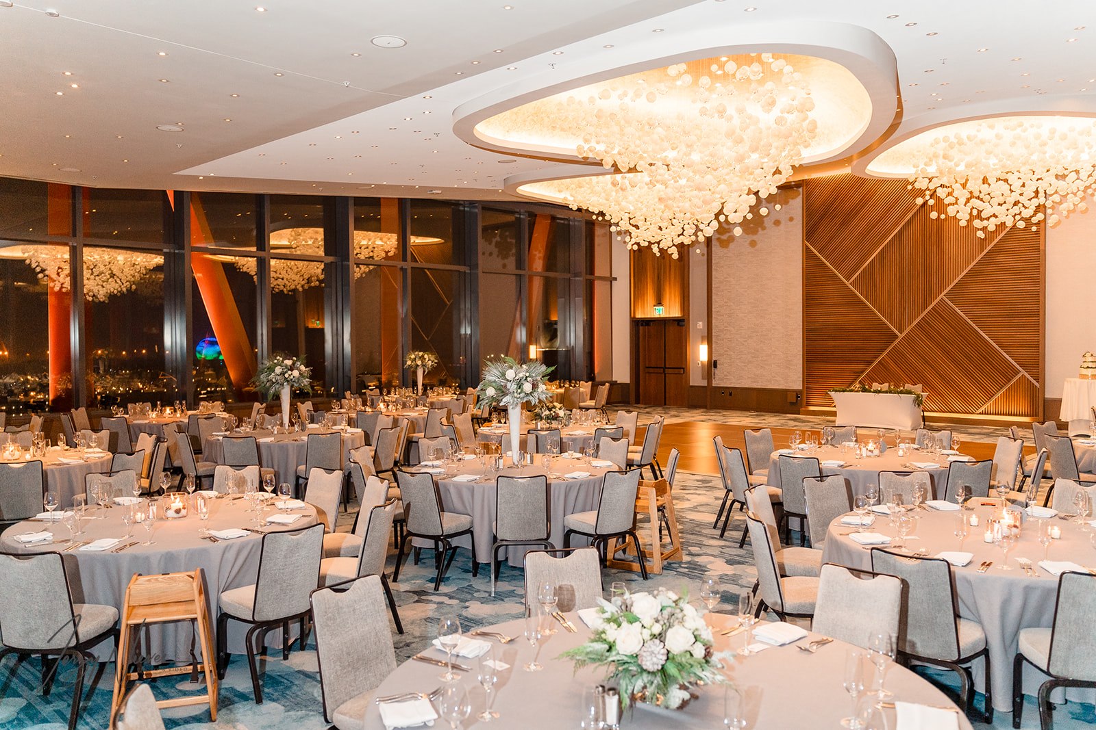 Elegant reception area at Disney Swan Reception Hall adorned with white tablecloths and flower bouquets on guest tables, with the couple's table situated on the stage.