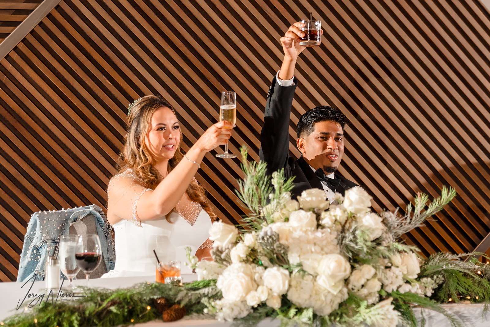 Close-up of Ravin and Nicole at the table on the stage, toasting with the guests in celebration at Disney Swan Reception Hall.