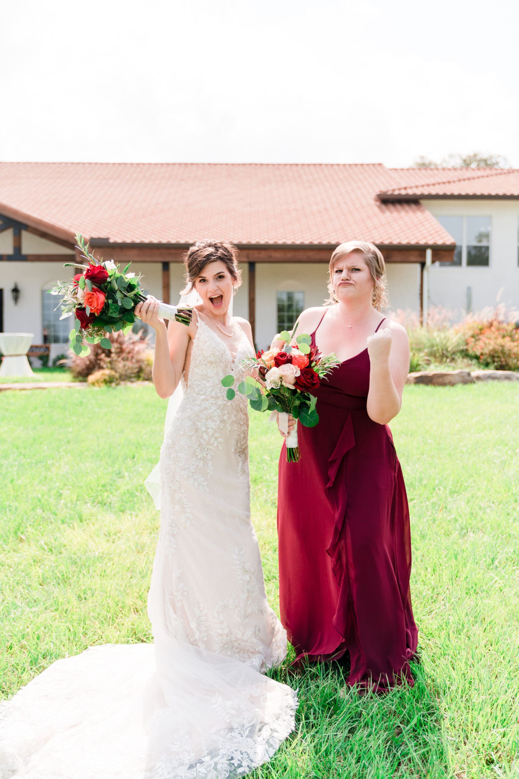 Bethany and her Maid of Honor goofing around in the garden at Sterling Event Venue, holding flowers and laughing.
