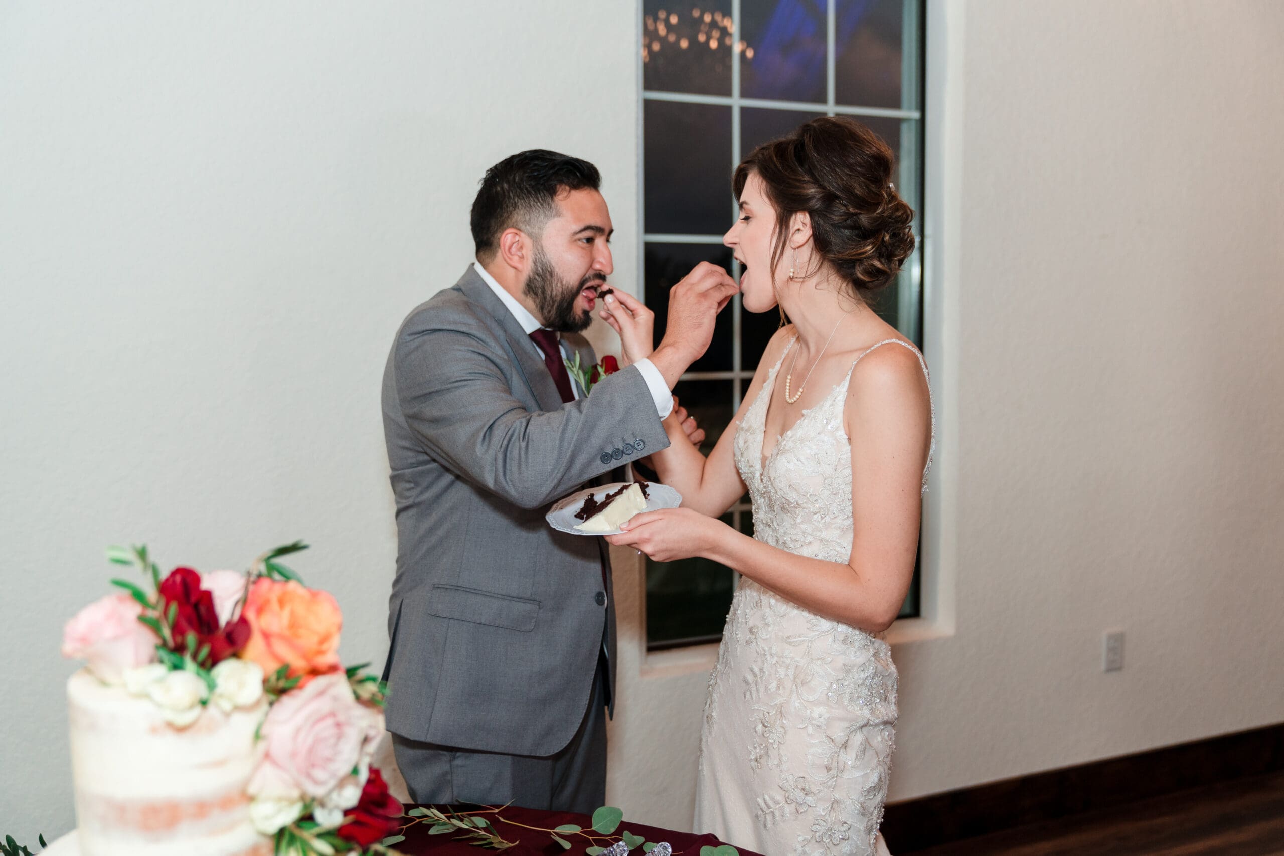 Bethany and Jonah feeding each other the first bites of their wedding cake simultaneously at the Sterling Event Venue Reception Center.