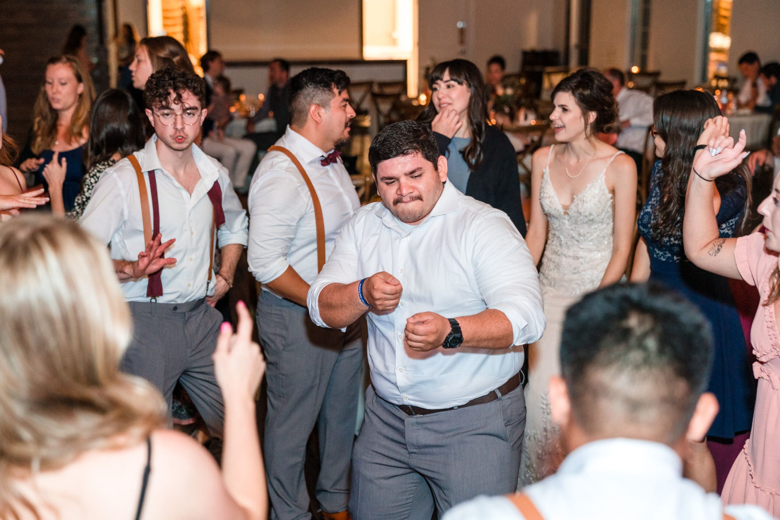 Guests enjoying themselves on the dance floor, with Bethany and Jonah in the background, at the Sterling Event Venue Reception Center.
