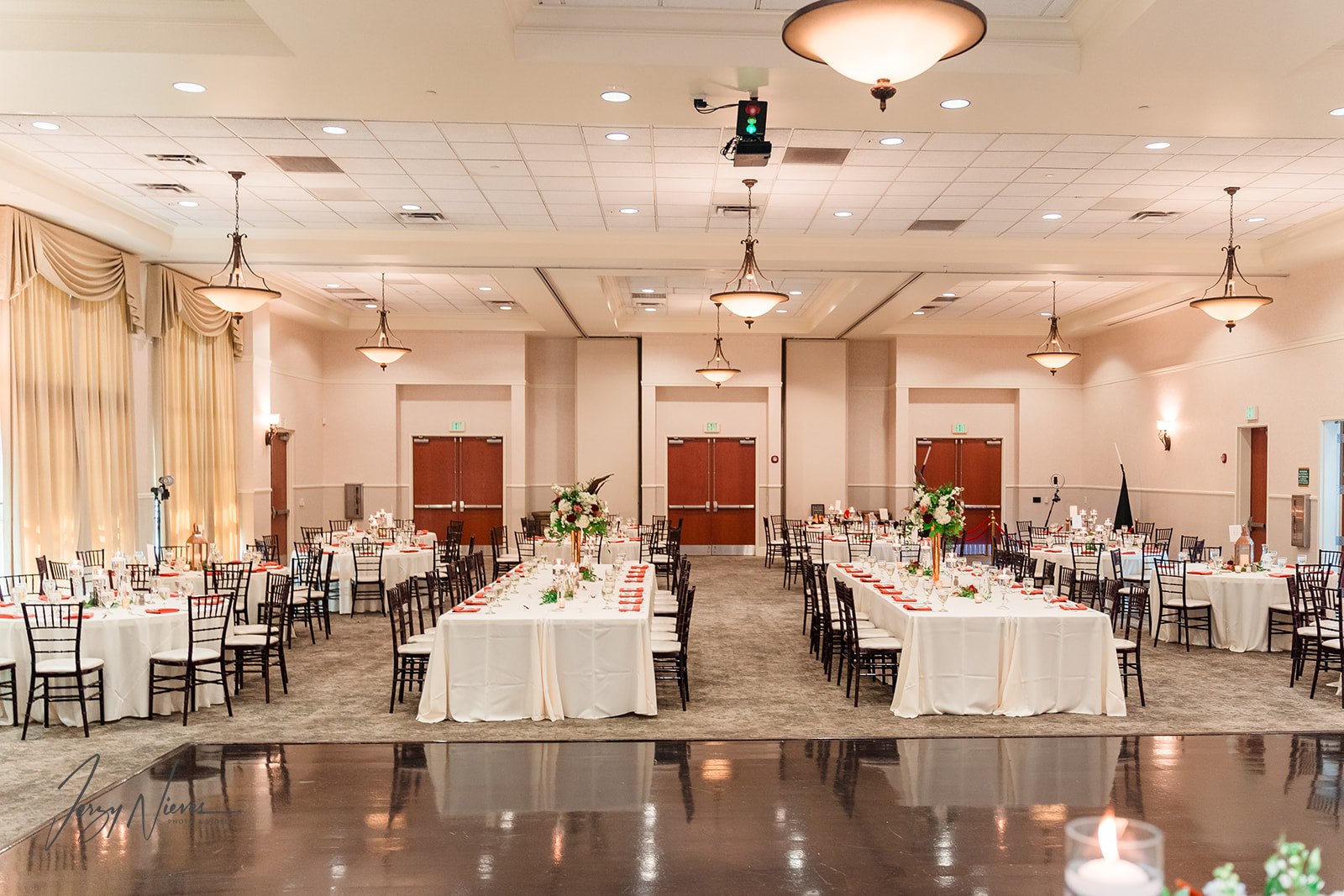 Empty reception center at Lake Mary Event Center decorated for Javon and Shelby's wedding with white tablecloths and flower bouquets.